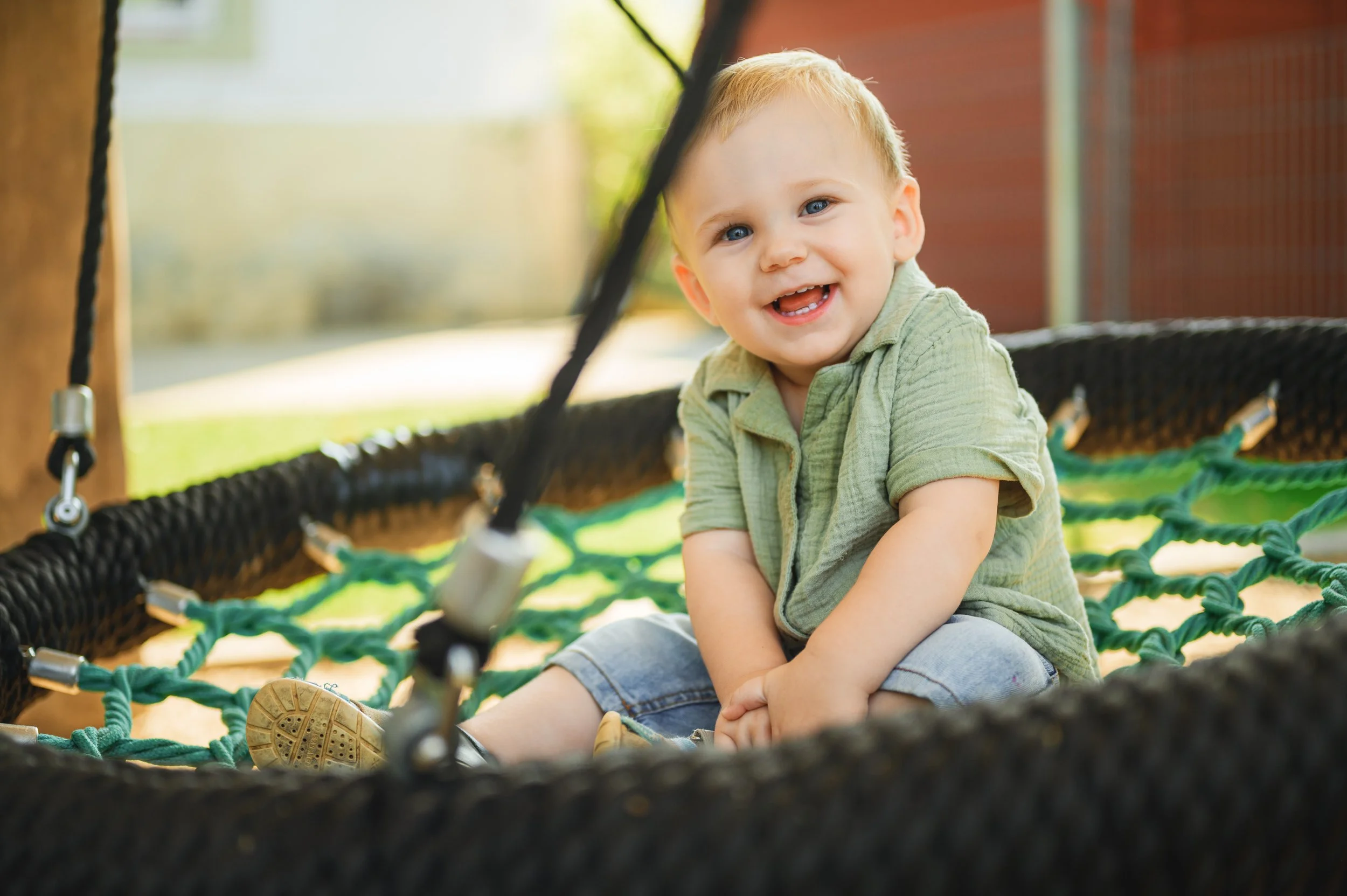 Natürliches Kita-Foto eines Kleinkindes auf dem Spielplatz, aufgenommen im Außenbereich bei weichem Tageslicht.
Fröhlicher Ausdruck, entspannte Haltung und ein ruhiger Hintergrund sorgen für eine warme, vertrauensvolle Bildwirkung.
Moderne Kita-Fotog