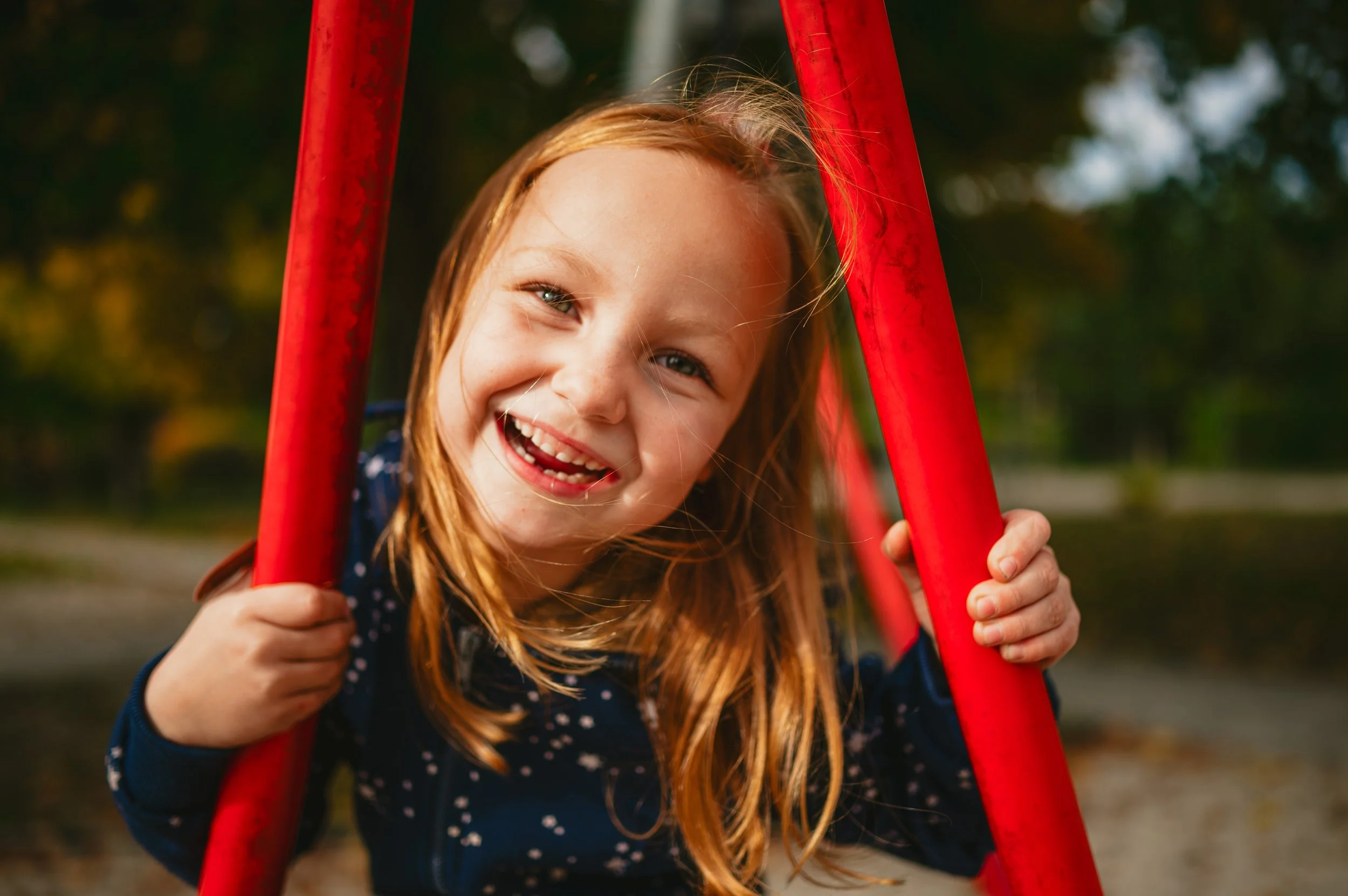 Natürliches Kita-Foto eines lachenden Kindes auf der Schaukel im Außengelände – moderne Kita-Fotografie ohne Zeitdruck.
