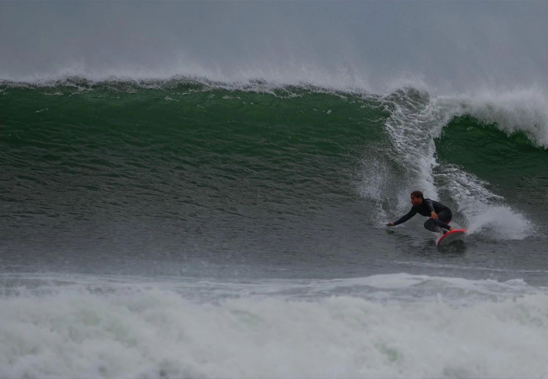 A person surfing on a large breaking wave in the ocean.
