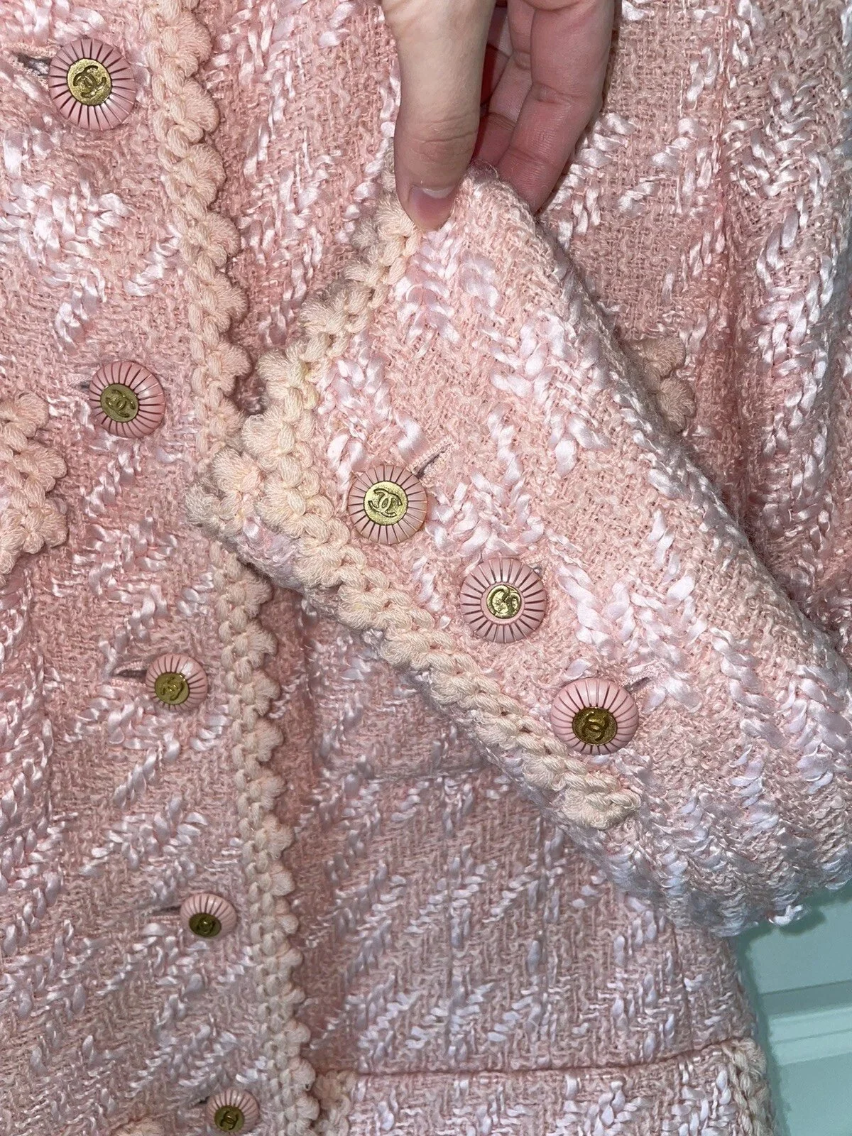 Professional garment rescue of a pink luxury tweed jacket, showing the intricate logo buttons and detailed braided trim.