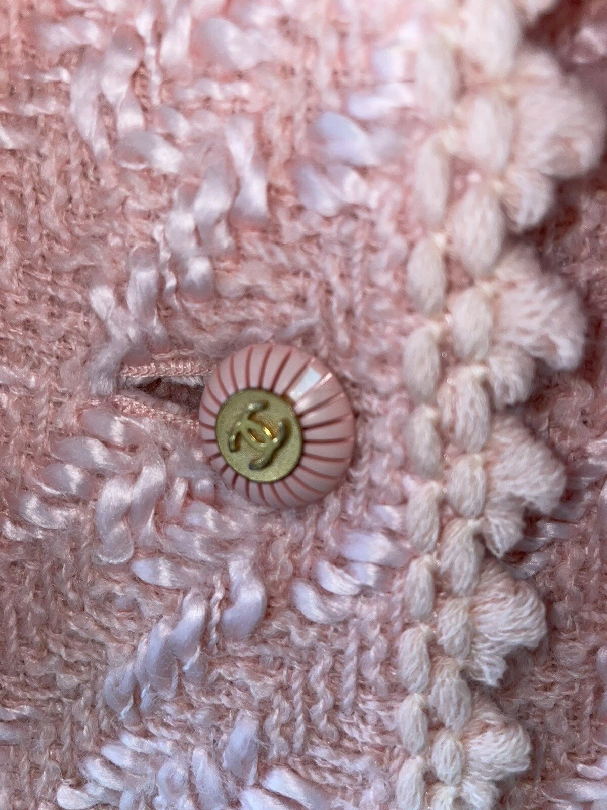 Close-up of a pink Chanel button on textured fabric, highlighting a luxury piece ideal for professional garment rescue.