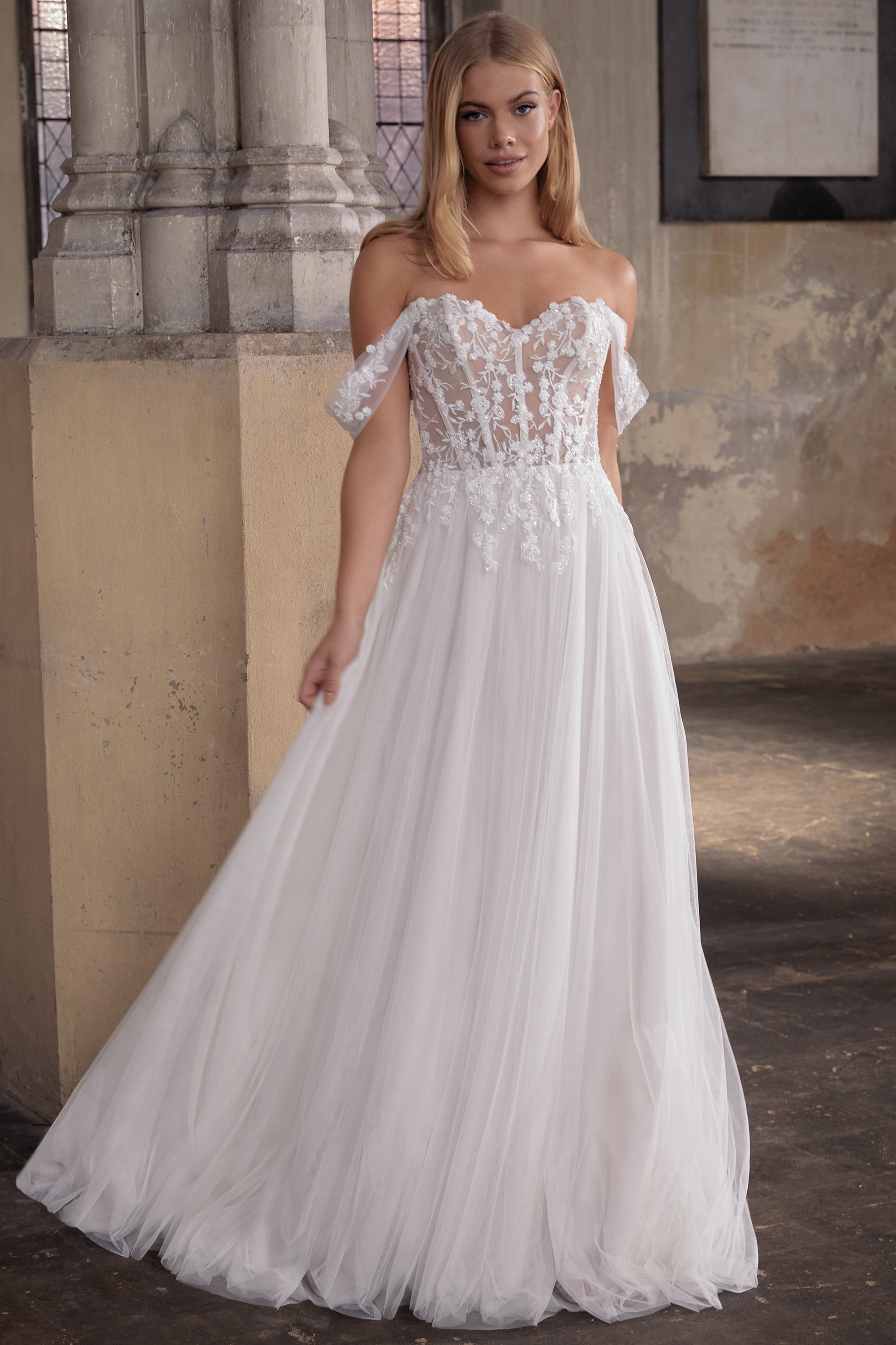 Brautkleid mit off-shoulder Design, Spitze und Tüllrock, model in einer historischen, steinernen Innenraum