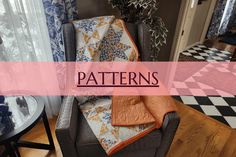 A gray armchair with a quilted blanket draped over it, in a room with hardwood floors and a black-and-white checkered floor in the background, with a side table and a plant nearby.