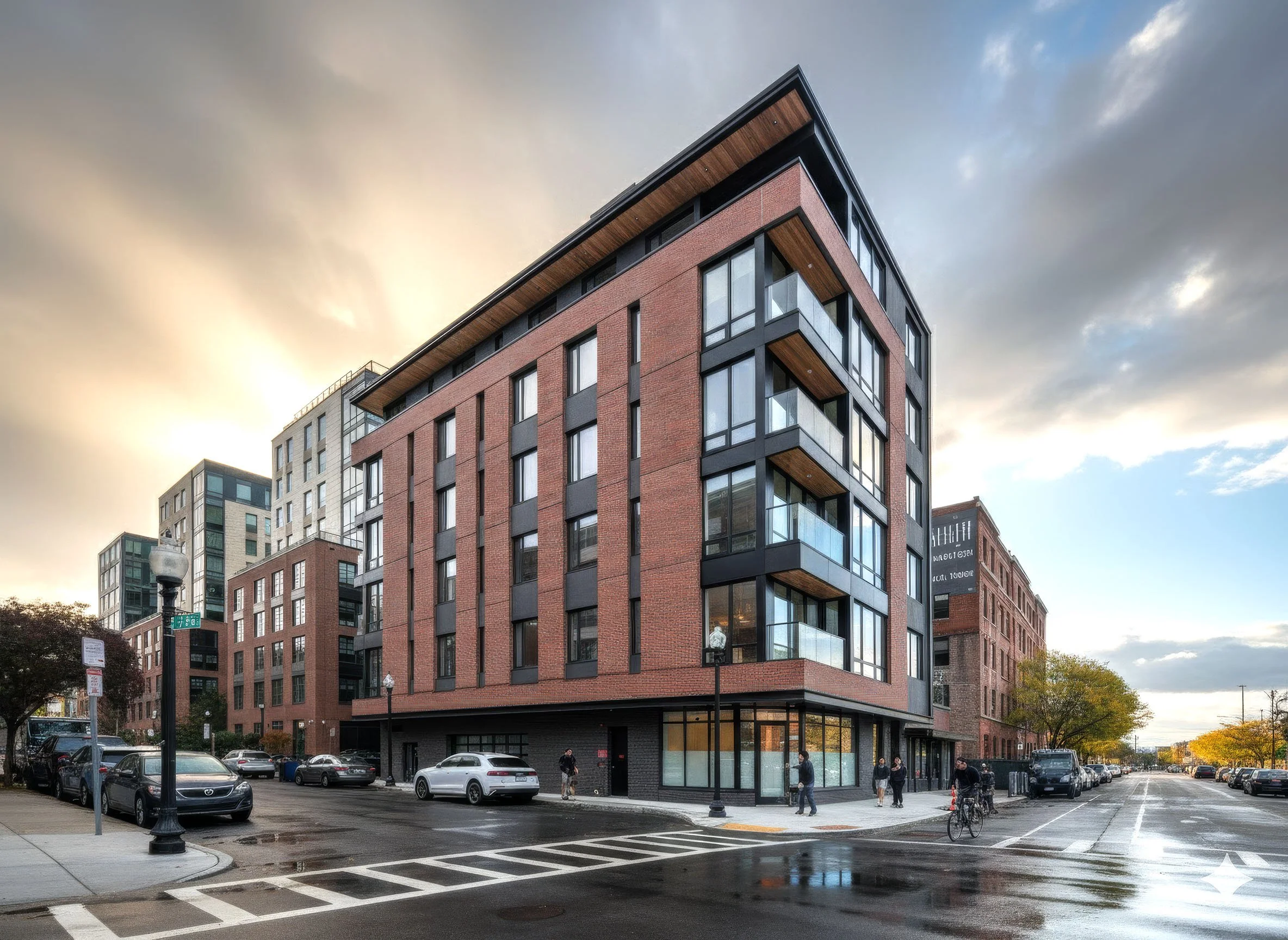Urban multifamily housing at sunset with pedestrian and street-level activity.
