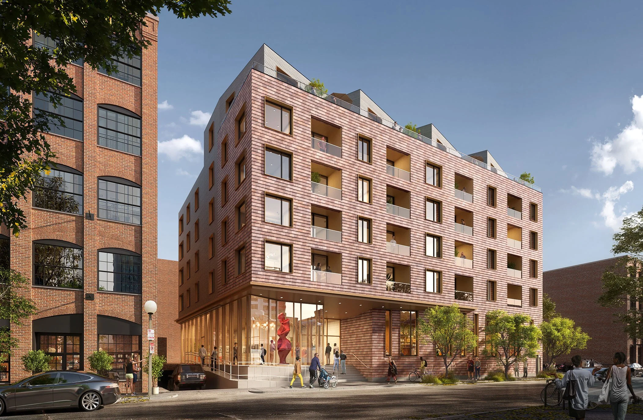 A modern multi-story building with a brick and metal facade, featuring large glass windows and balconies, located on a busy street with pedestrians, cars, and trees.