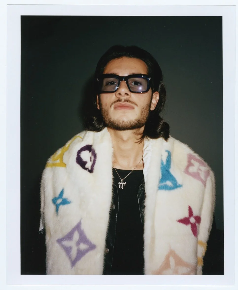 Jeune homme portant des lunettes de soleil, un foulard en fausse fourrure avec un imprimé coloré dans le style Louis Vuitton.