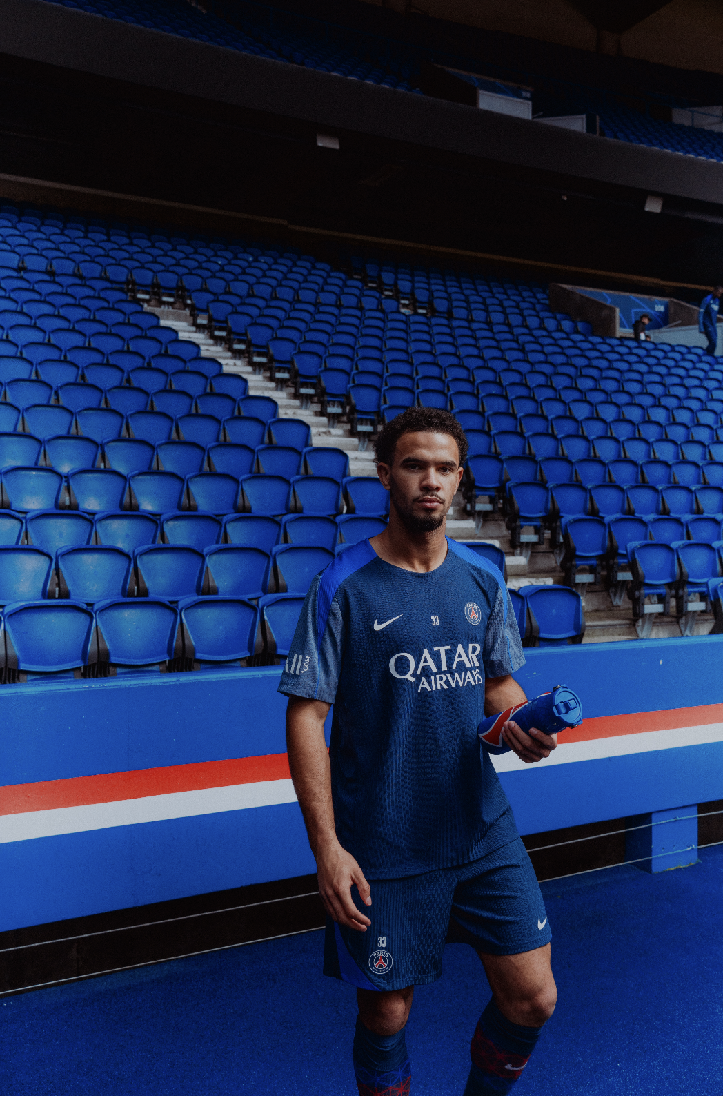 Un joueur de football en tenue du PSG dans un stade vide.