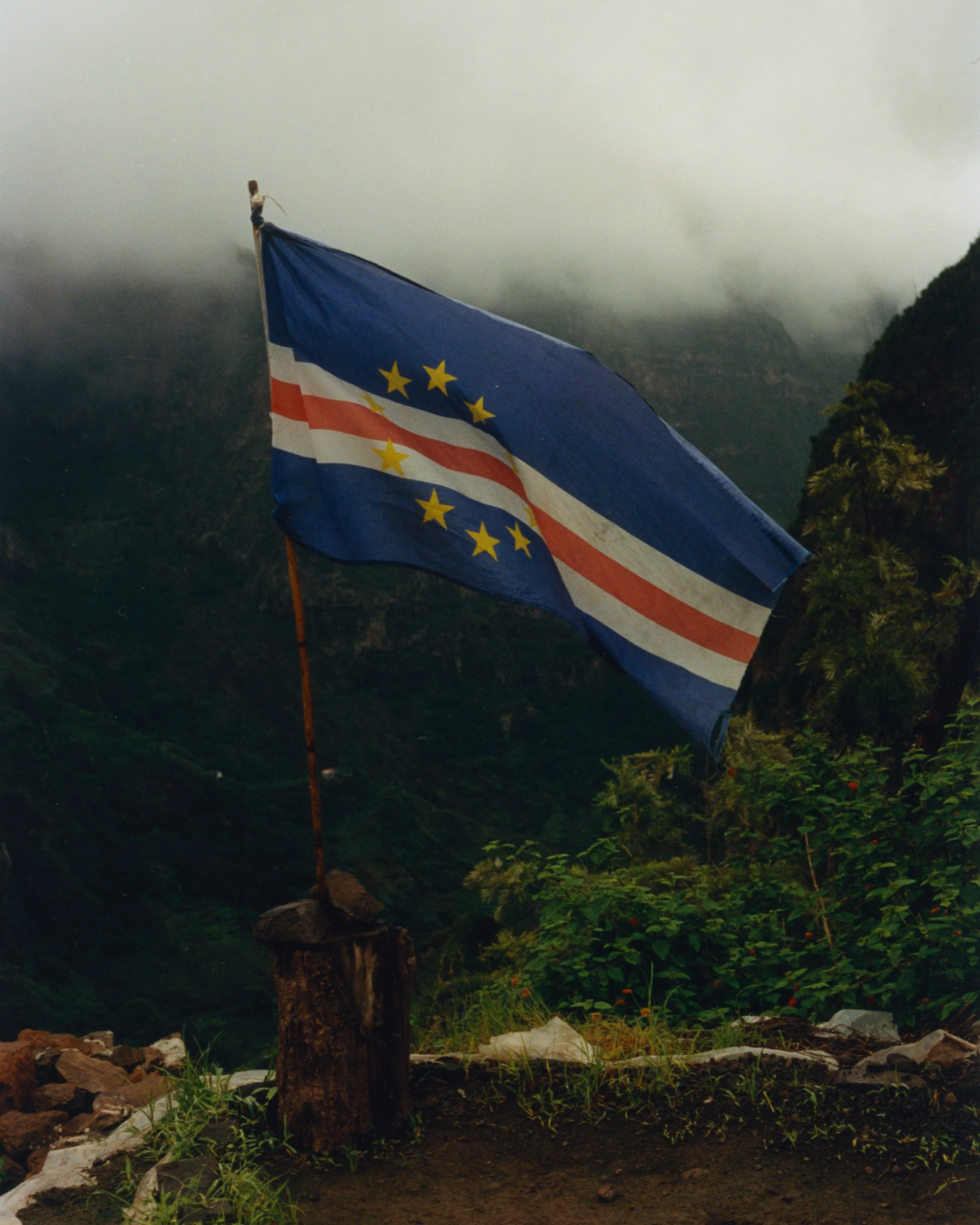 Drapeau de São Tomé-et-Príncipe volant dans un paysage de montagnes verdoyantes et brumeuses.
