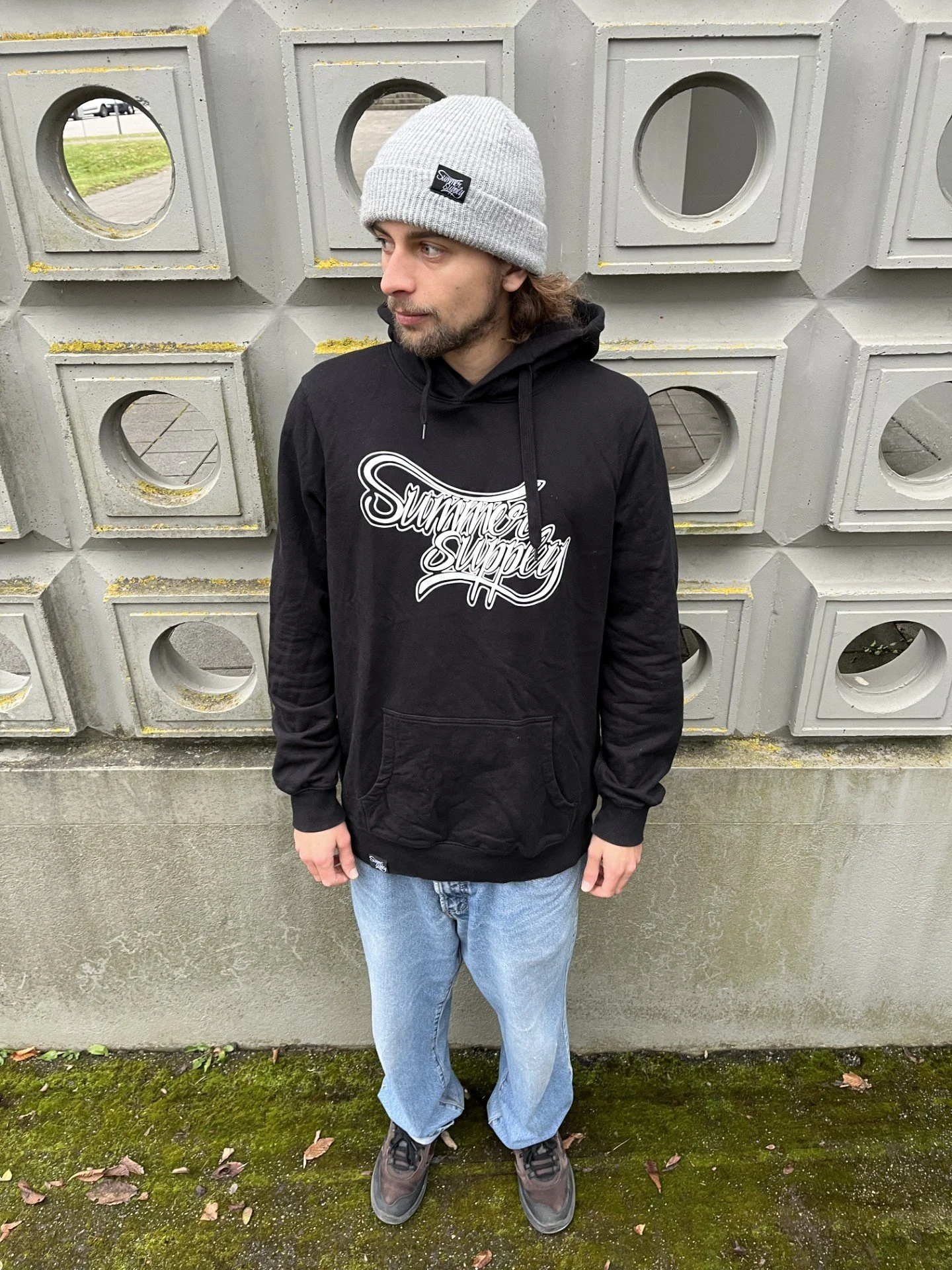 Person in einer schwarzen Hoodie, die auf einen ruhigen See blickt, mit Kamera in der Hand, bei Dämmerung.