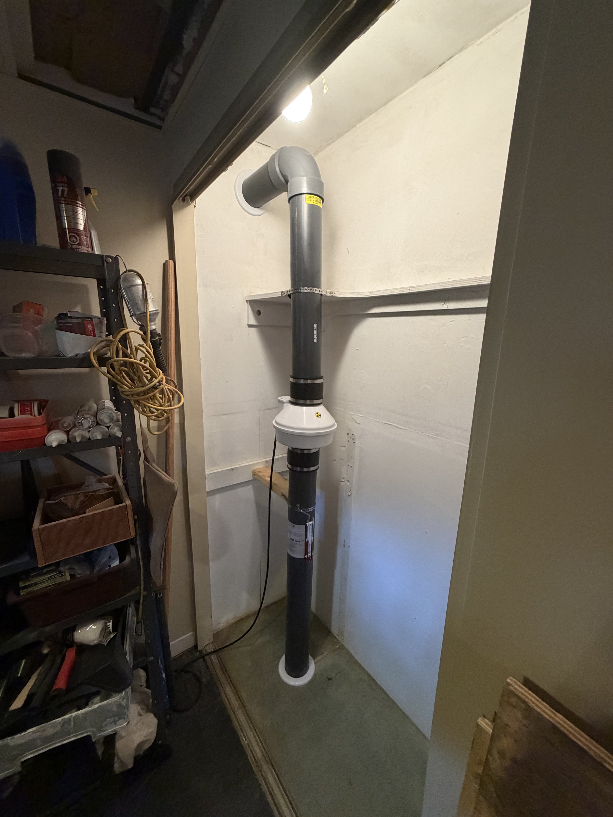 Installation d'un système de dépressurisation active du sol (DAS) à l'intérieur d'une garde-robe résidentielle à Repentigny. Le système a été positionné stratégiquement afin de minimiser l'encombrement et de préserver l'espace de rangement, avec une 