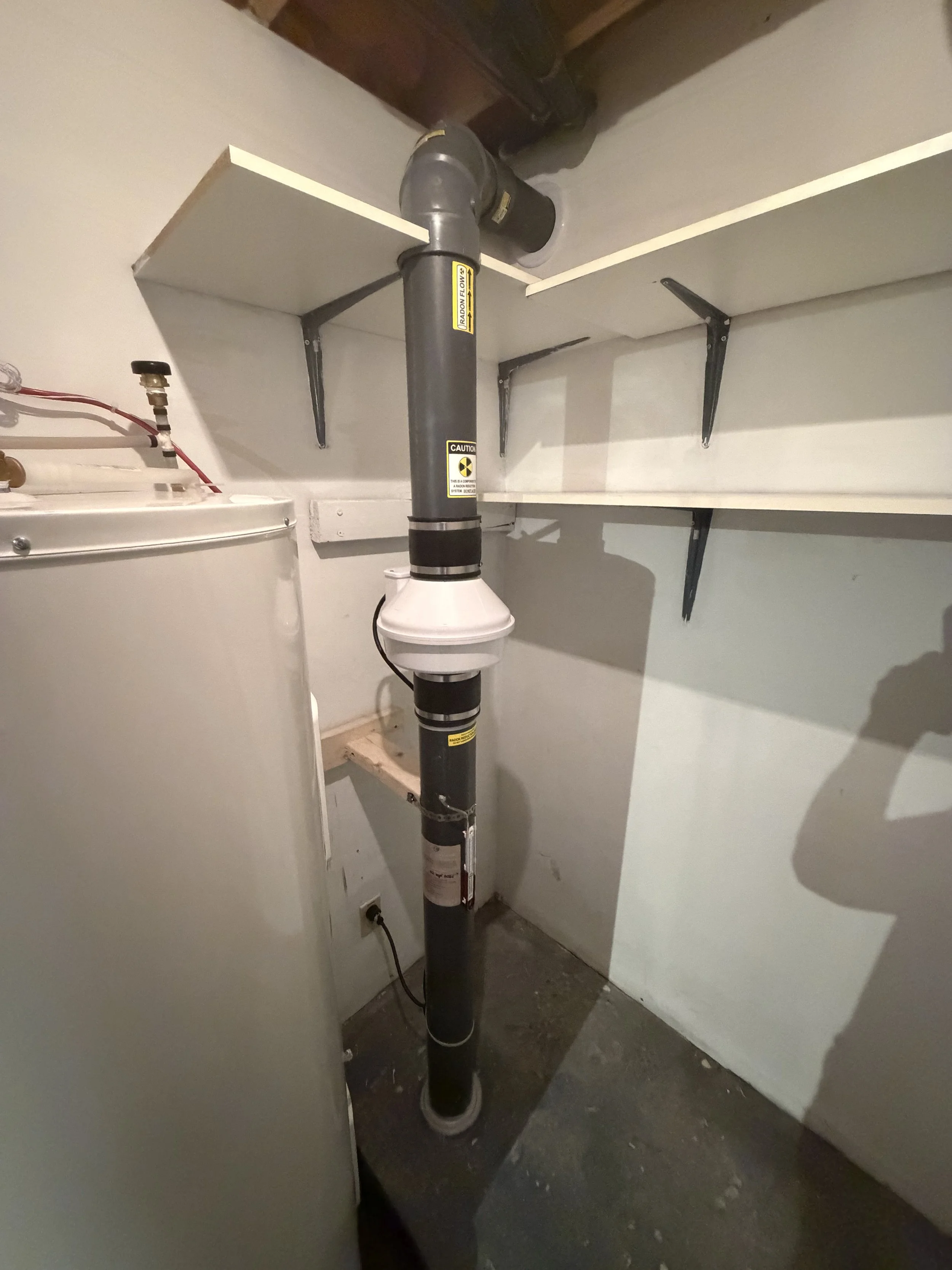 Installation d'un système d'atténuation du radon soigneusement intégré à travers les tablettes d'un espace de rangement à Repentigny. Le trajet de la tuyauterie a été optimisé afin de préserver la fonctionnalité des tablettes tout en assurant une ins