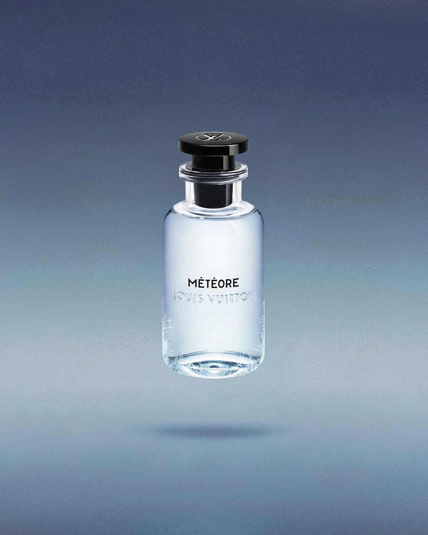 A clear glass perfume bottle labeled 'MÉTÉORE' by Louis Vuitton, floating above a soft grey background.
