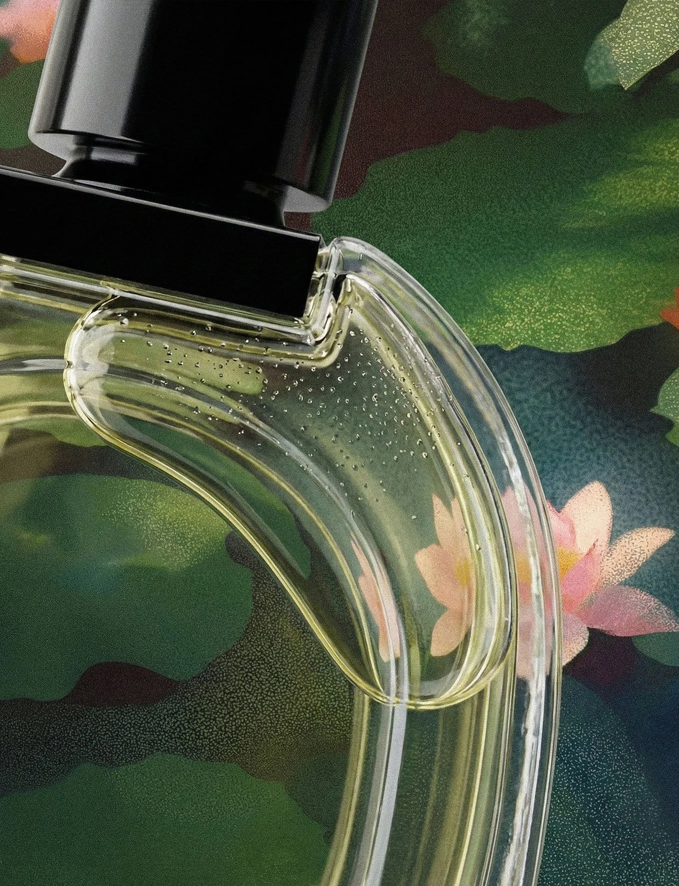 Close-up of a perfume bottle with clear liquid and a black cap, placed on a green and pink floral-patterned surface.