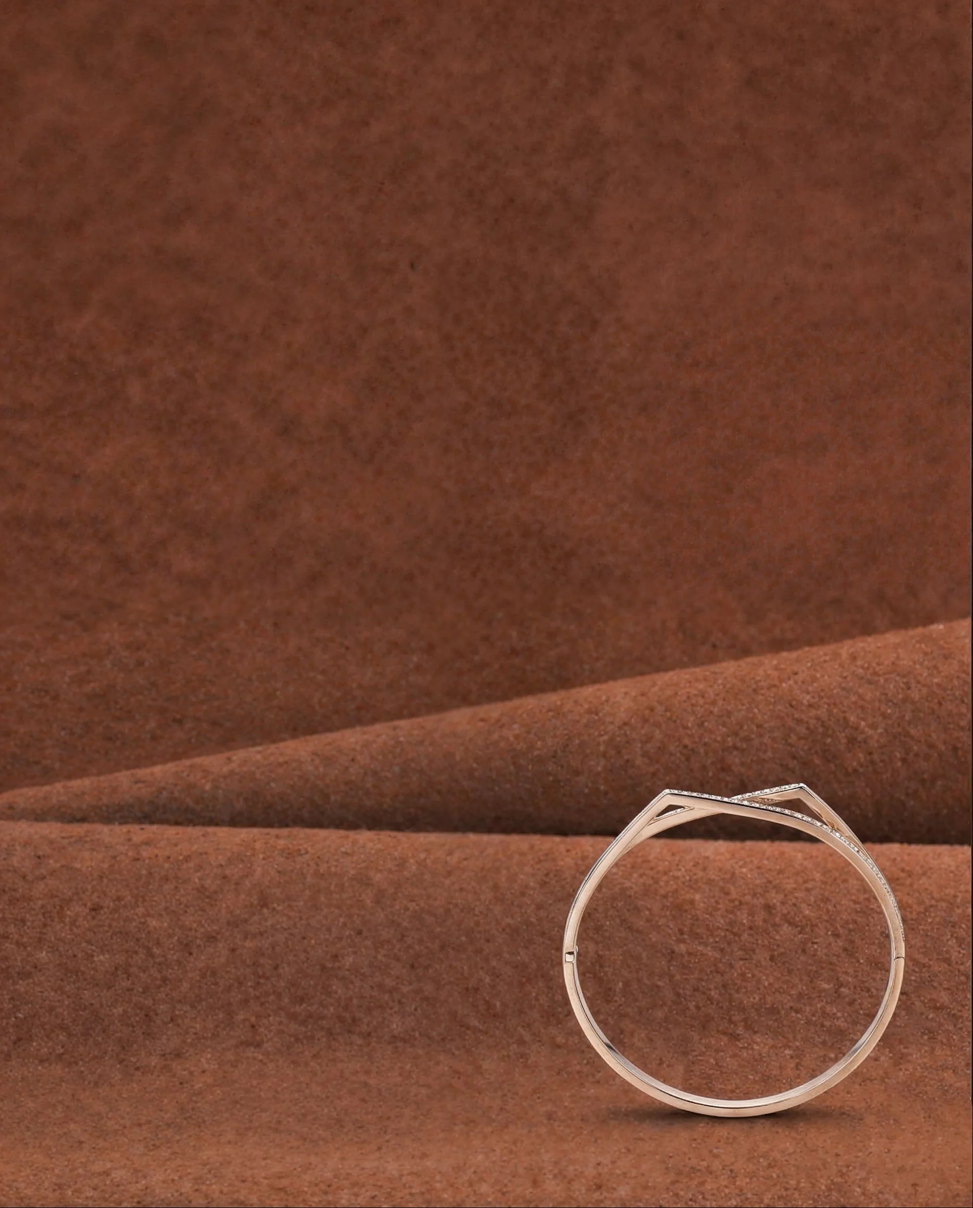 A silver ring with a small diamond, displayed on a brown textured fabric surface.