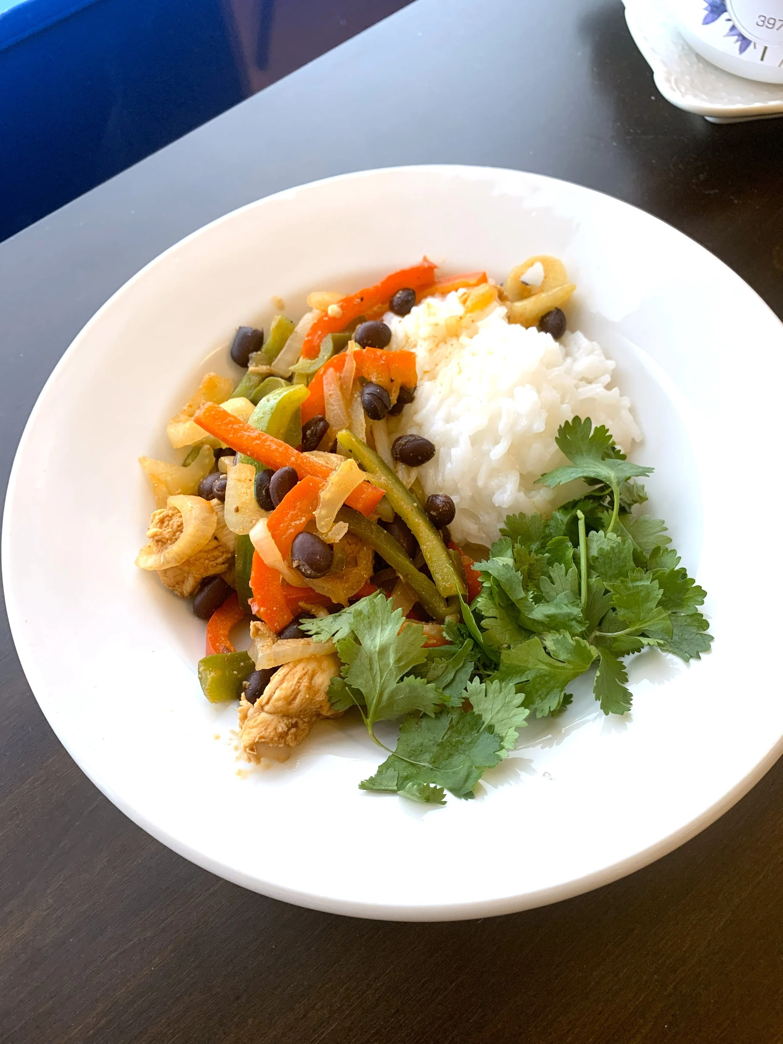 white plate with chili lime chicken fajitas, white rice and green cilantro leaves
