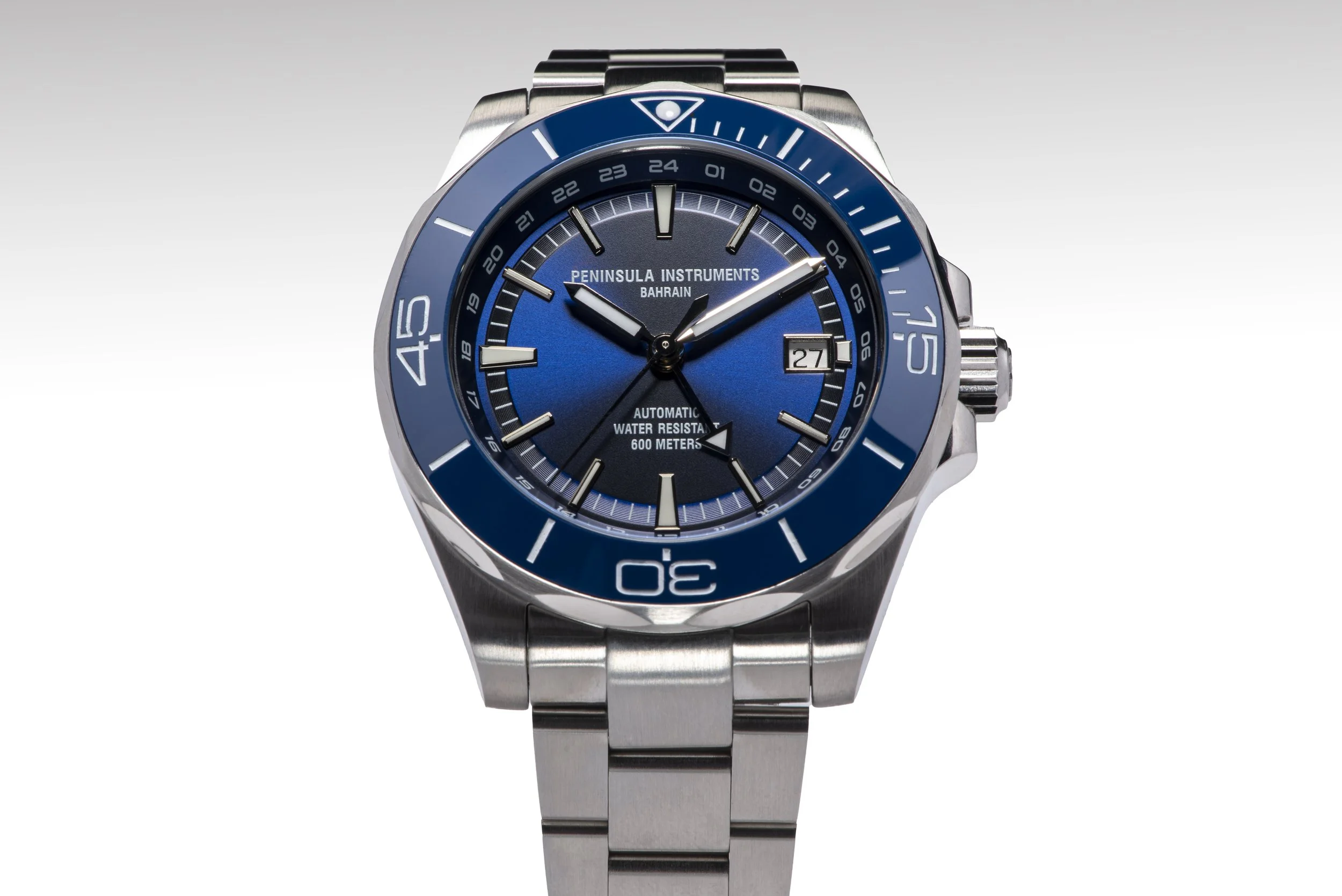 Blue and silver diver's watch with a metal band, rotating bezel, and a date display at 3 o'clock. The watch face includes text indicating it is automatic and water resistant to 600 meters.