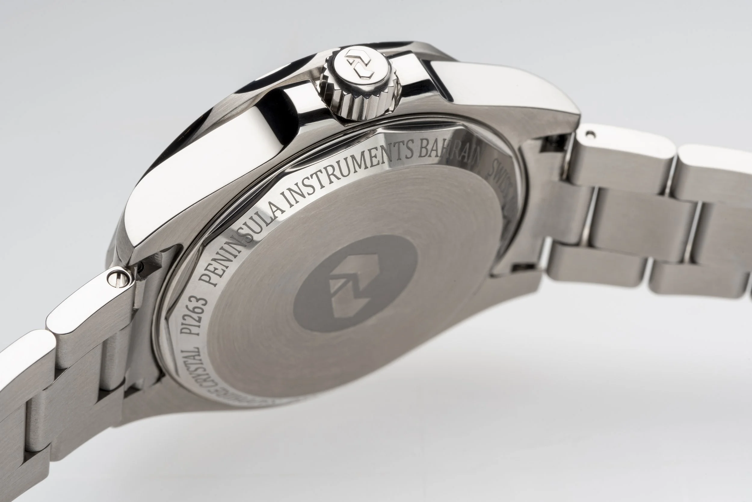 Close-up of a stainless steel wristwatch featuring a metal bracelet and a crown with a logo.