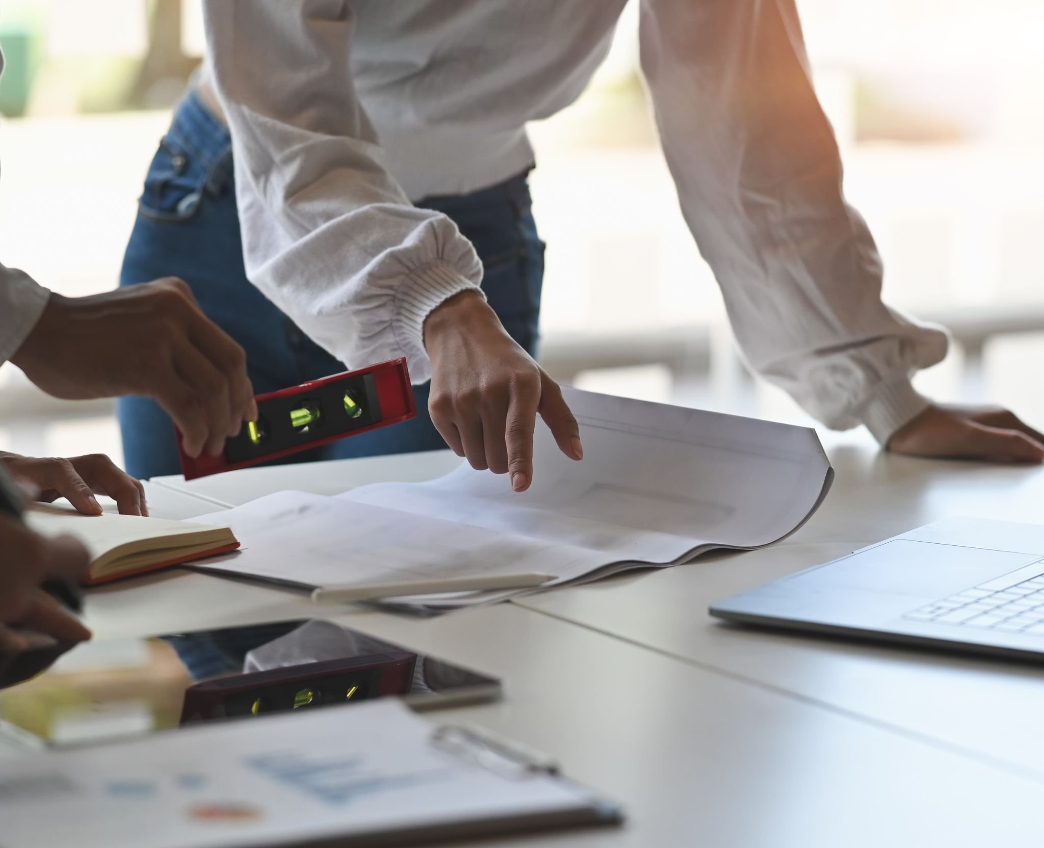 People working on a project with papers, a laptop, and a level on the table.