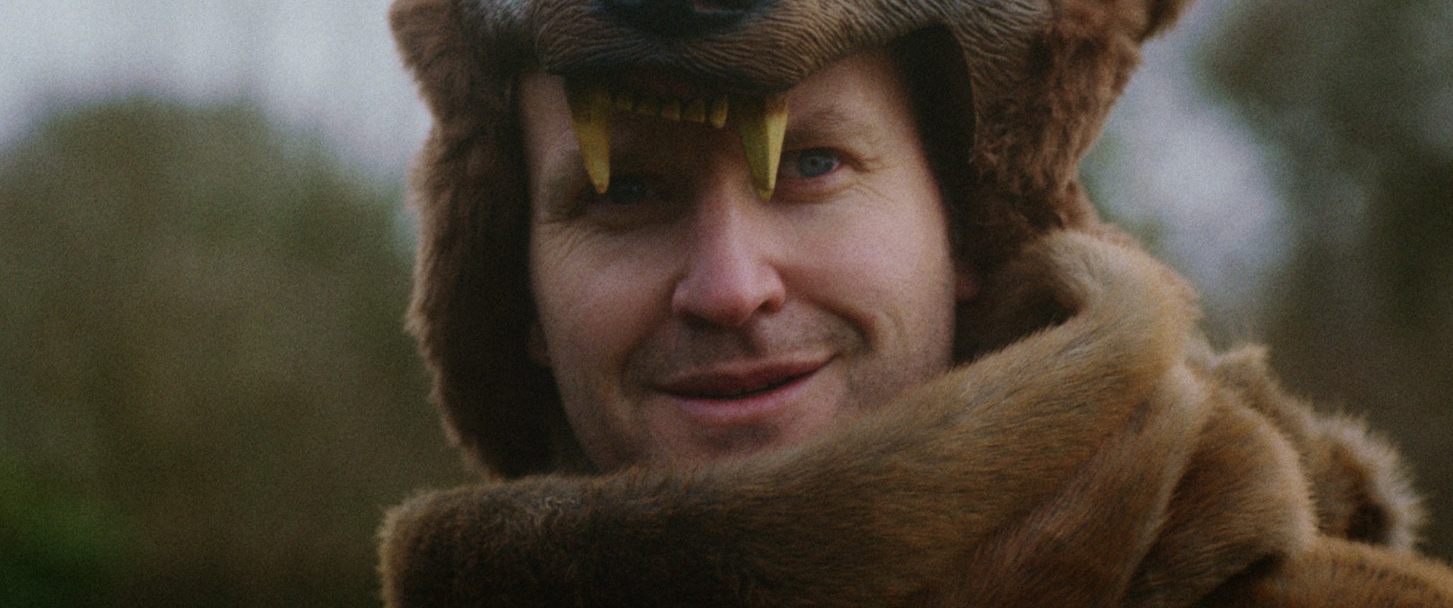Man wearing a bear costume with bear head hood, outdoors
