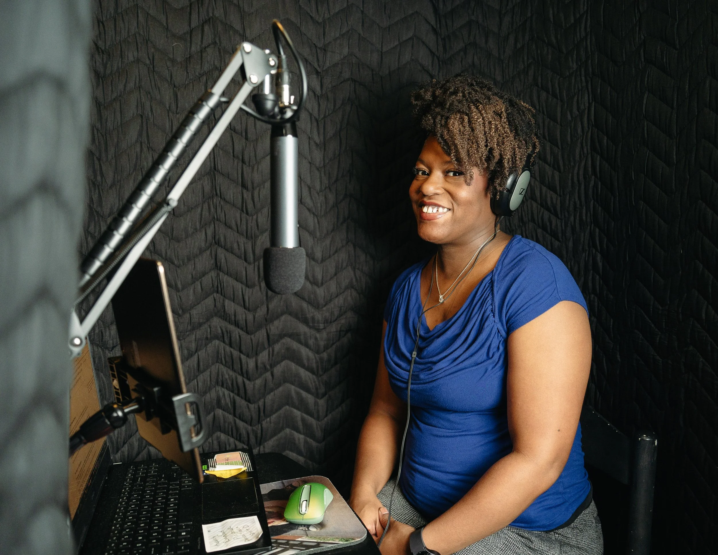 woman sitting in a soft side sound booth in front of a microphone