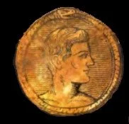 Close-up of an ancient gold coin featuring a profile of a person's head with stylized hair.