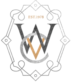 A logo with a gray and black circular design featuring overlapping W and V letters, and a banner at the top with 'EST. 1978' written in orange, all enclosed in an ornate border.