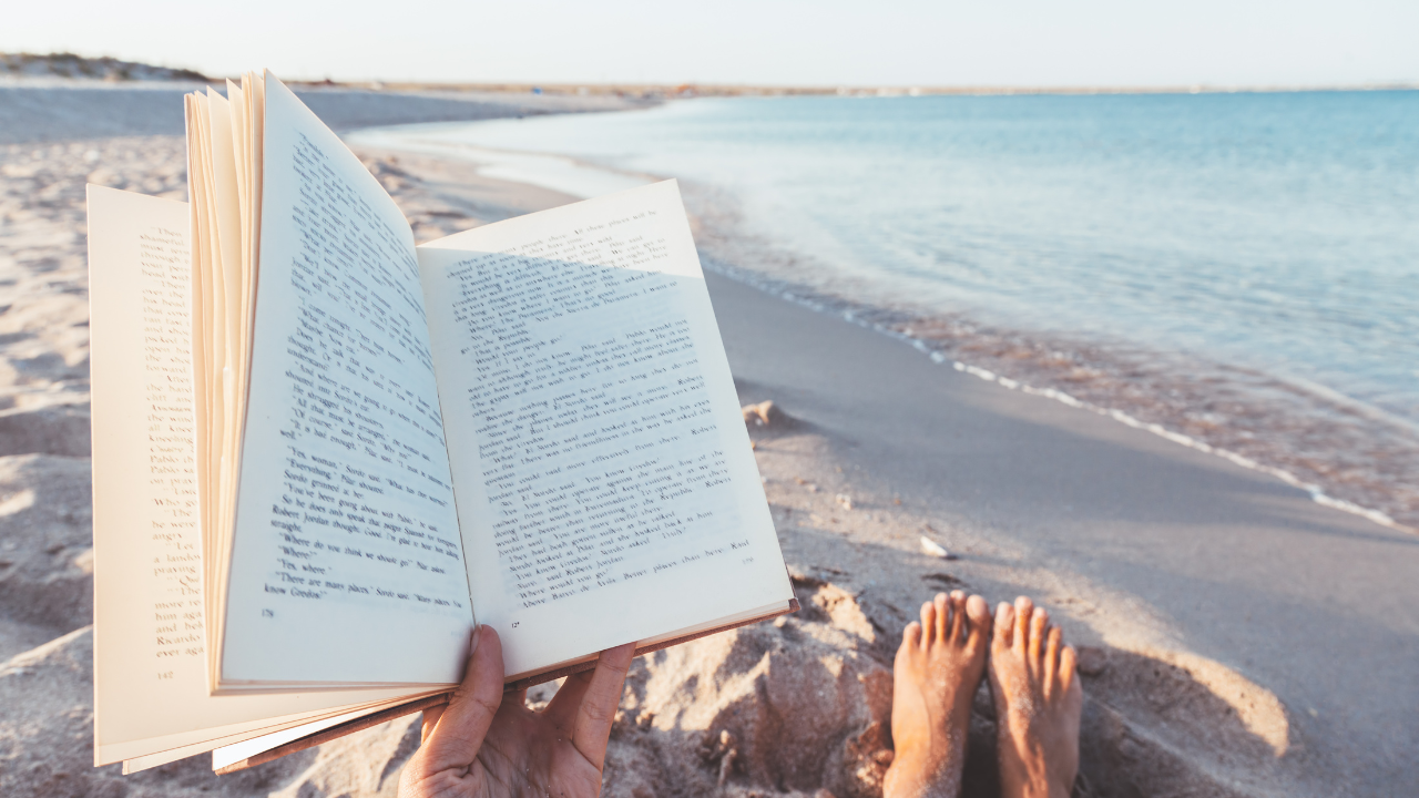 Midlife woman reading on the beach reflecting on mood changes during perimenopause.