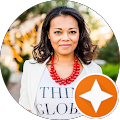 Portrait of a woman wearing a white blazer, red necklace, and a shirt with text, with a star icon overlay in the corner.