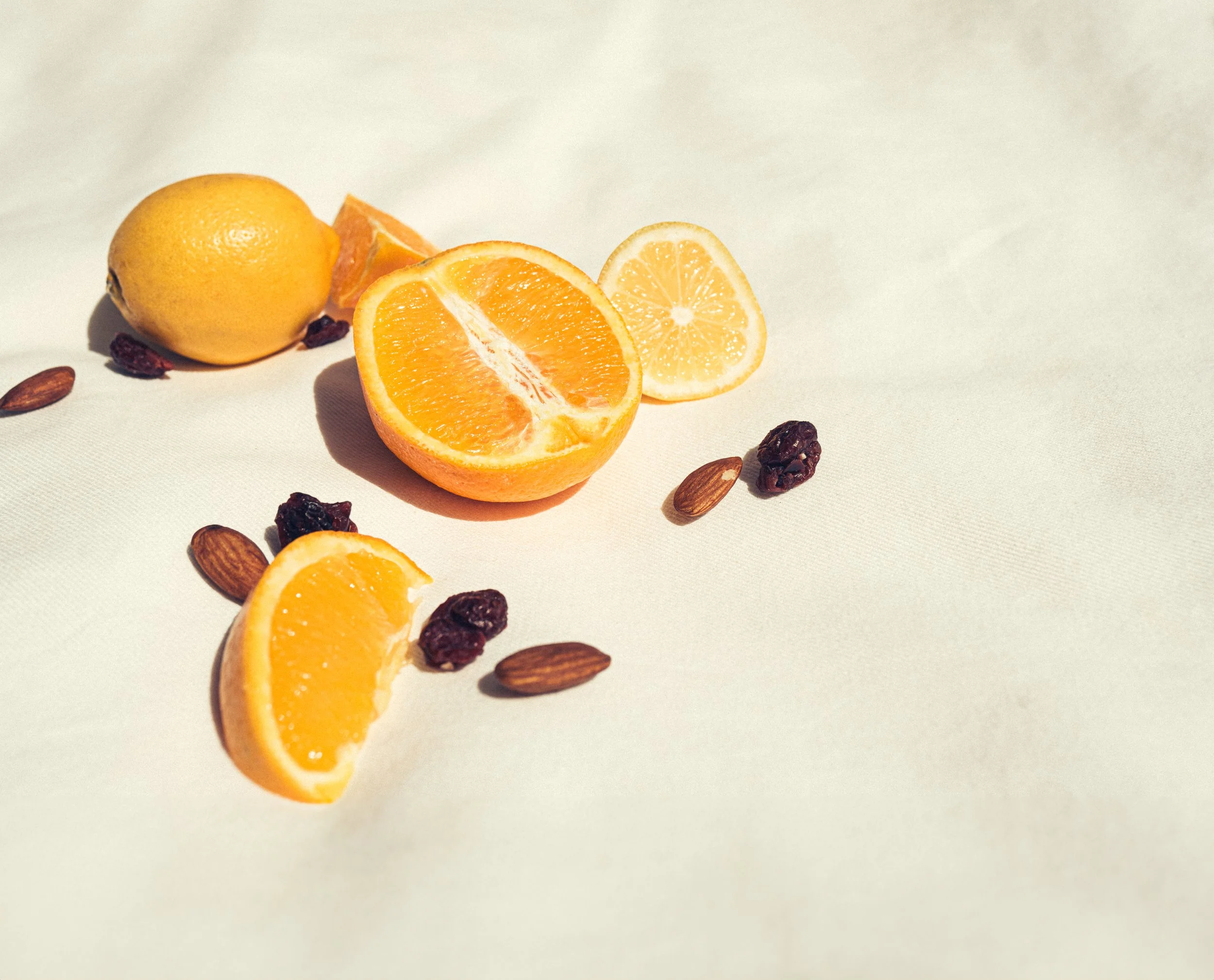 Sliced orange, dried cranberries, and almonds on a picnic blanket.