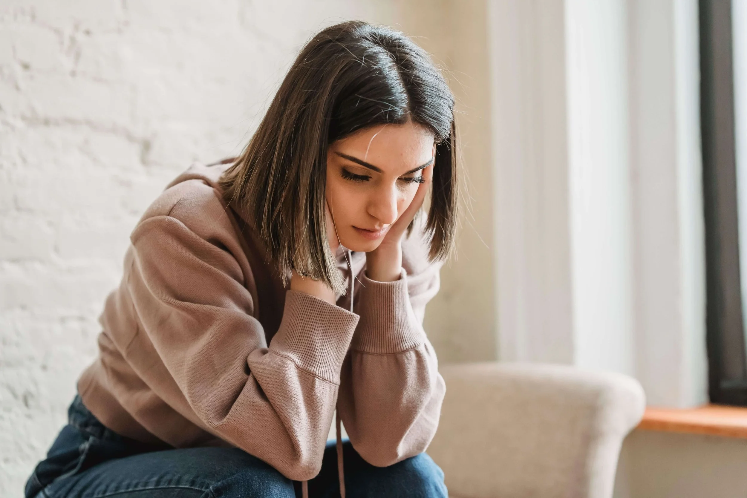 Sad and anxious woman experiencing emotional distress related to feeling “good enough” and concerns addressed through perfectionism therapy in New York.