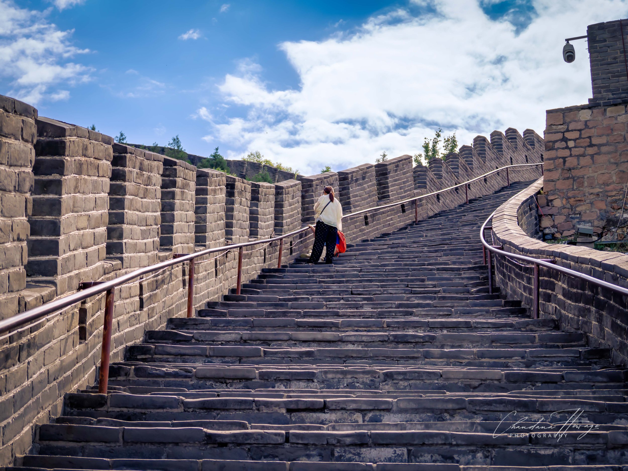 The changing pattern of the wall highlights a brilliant piece of Ming Dynasty military engineering known as HERRINGBONE WALLING or stepped battlements. 
The tops of the bricks are laid in a diagonal, zig-zag pattern, creating a "sawtooth" profile tha