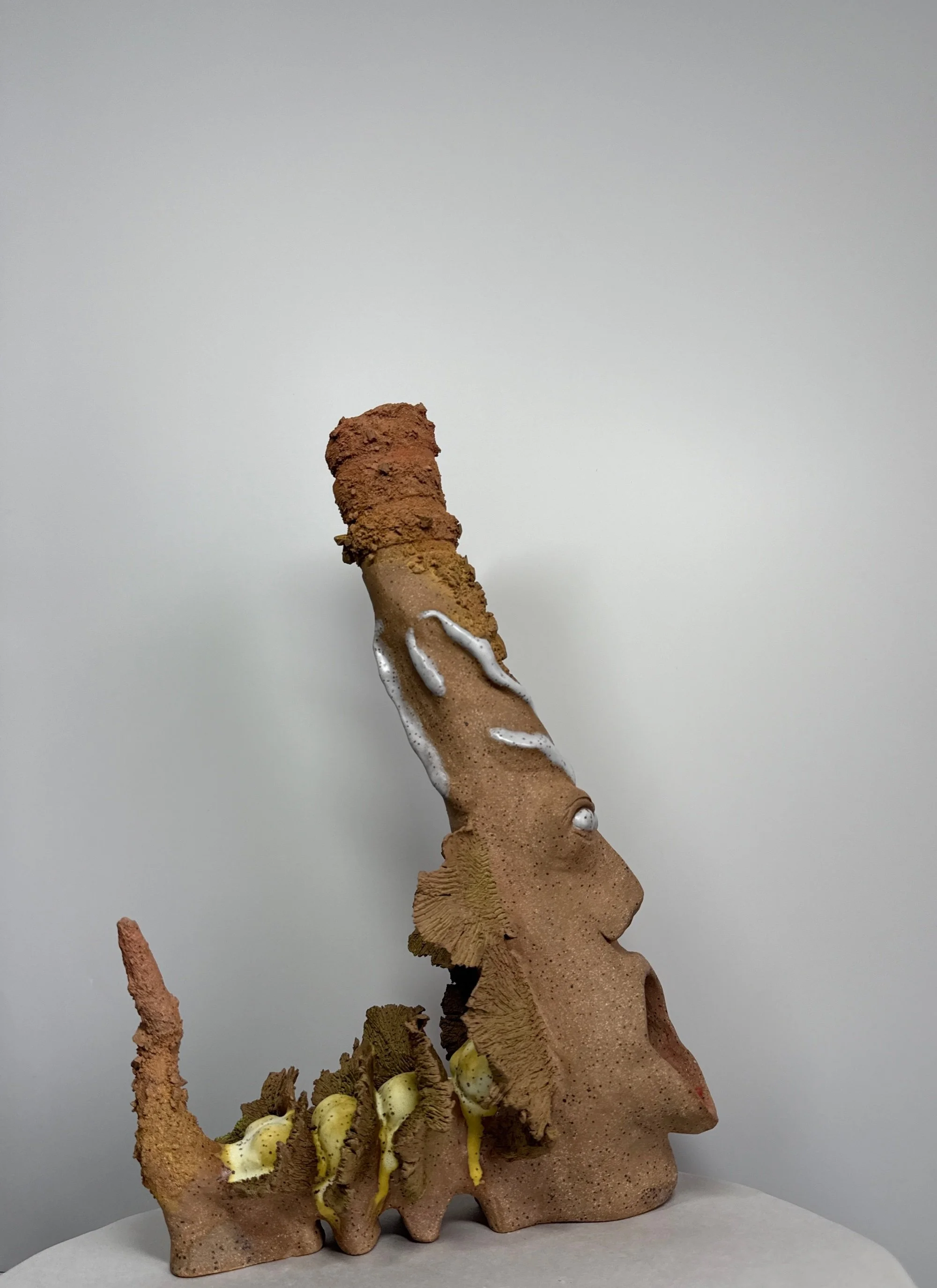 A warm toned stoneware ceramic sculpture titled: ‘Rebirth of a Sunny Day’, featuring a dragon-like shape with wings and pointed tail, a functional candle chamber at the base, and a tall turban that allows for smoke to come out of the top.
