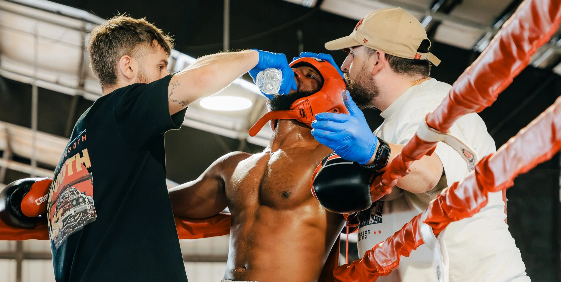 Boxers receiving medical treatment in a boxing ring with assistants helping an injured boxer.