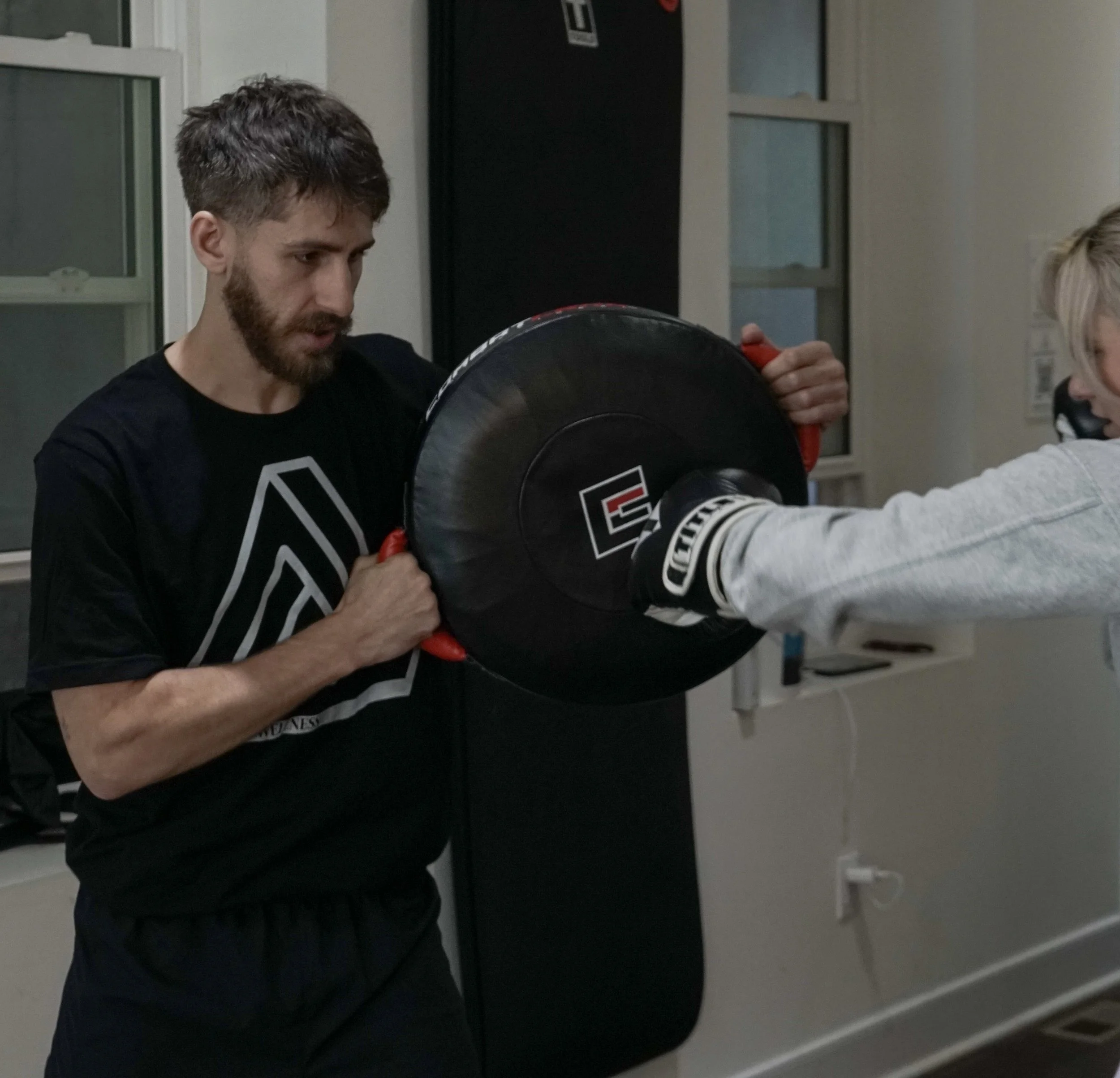 Coach Ben holds for a punch during a private boxing lesson at Triad Wellness Philly.