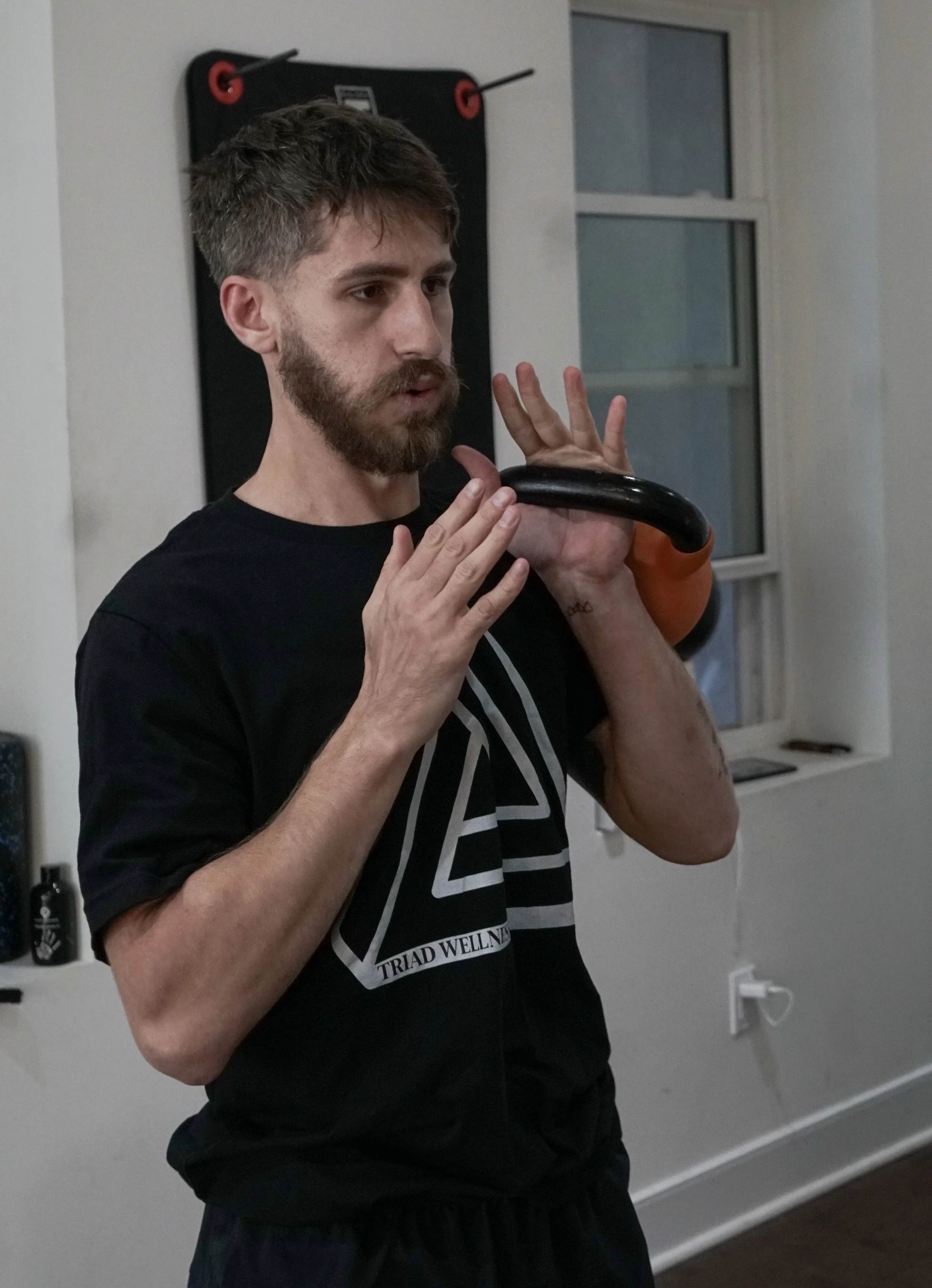 Coach Ben uses a kettlebell during a personal training session at Triad Wellness Philly.