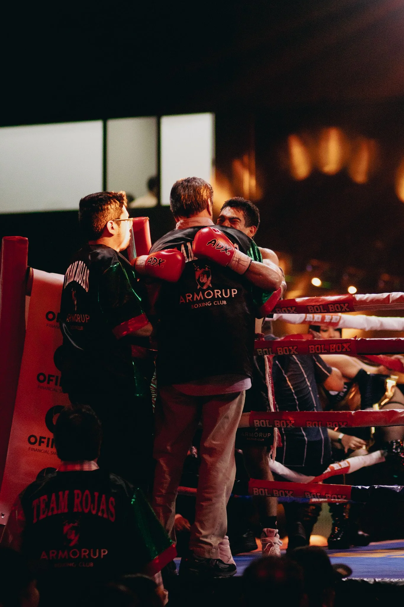 Entrenador y boxeadores en un ring de boxeo en un gimnasio, celebrando una victoria.