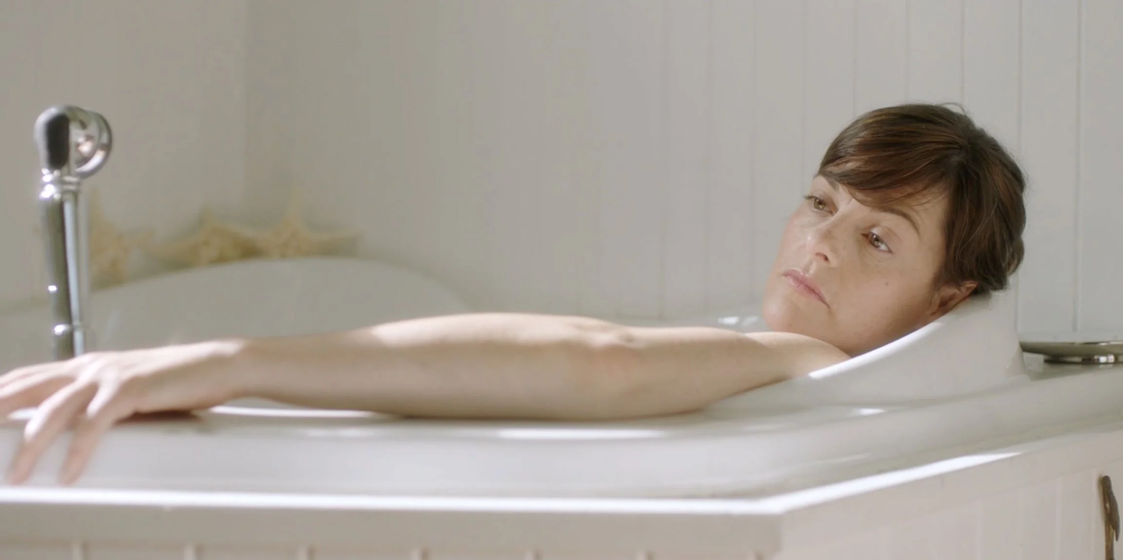 Woman lying in a vintage bathtub looking contemplative.