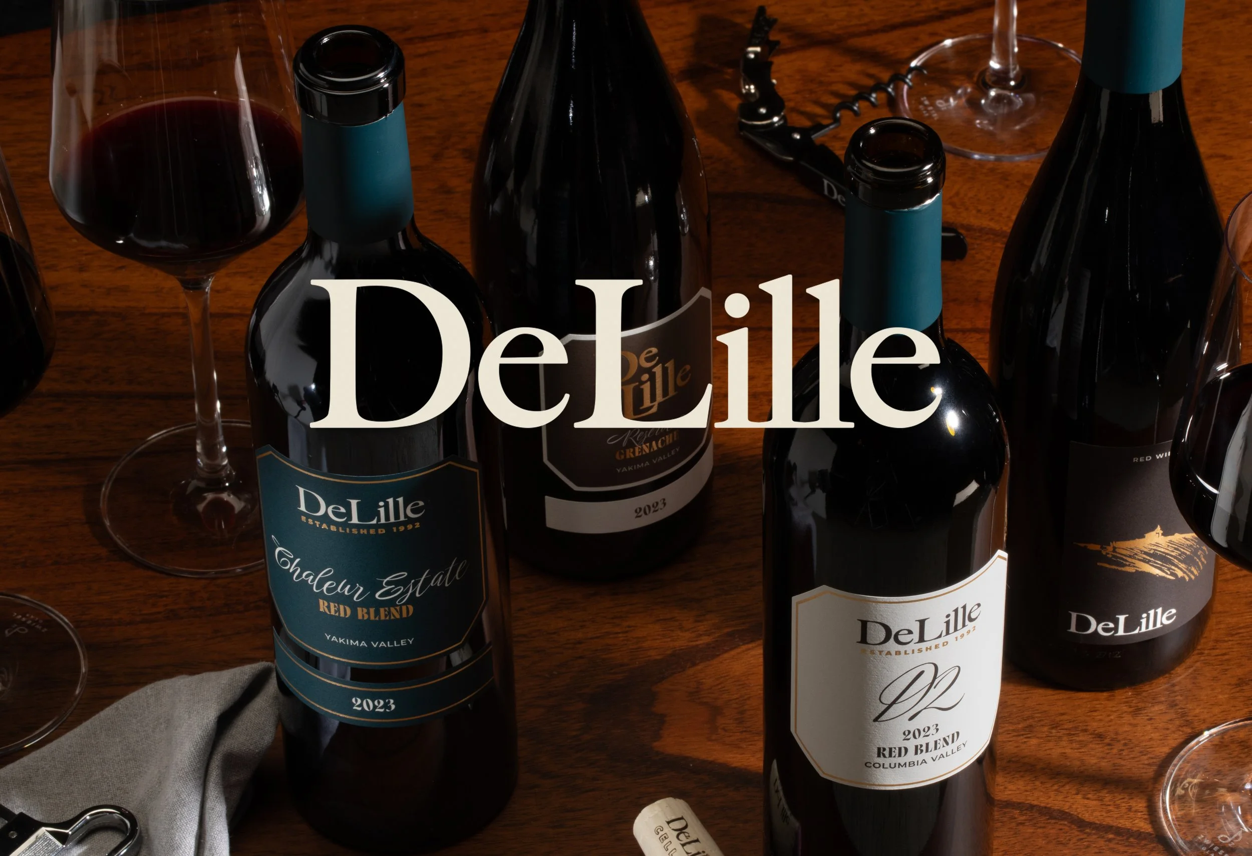 image of wine bottles on a table with new DeLille logo over the top