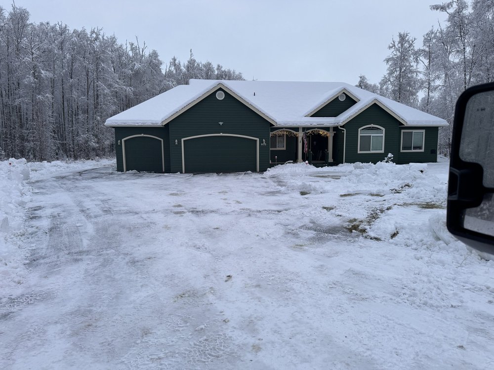 Green house with snow covered roof and plowed driveway in Wasilla, Alaska