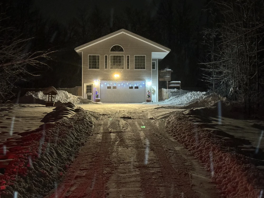 House lit up at night with a freshly plowed driveway in Wasilla, Alaska