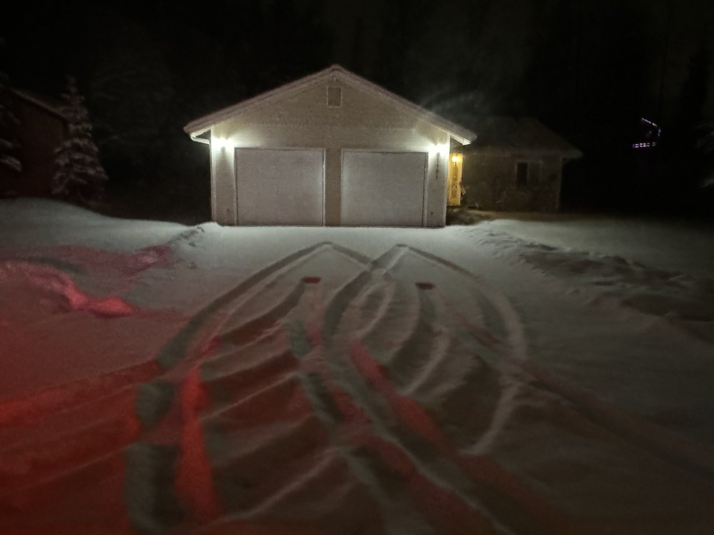 Lit garage with a plowed driveway at night in Anchorage, Alaska