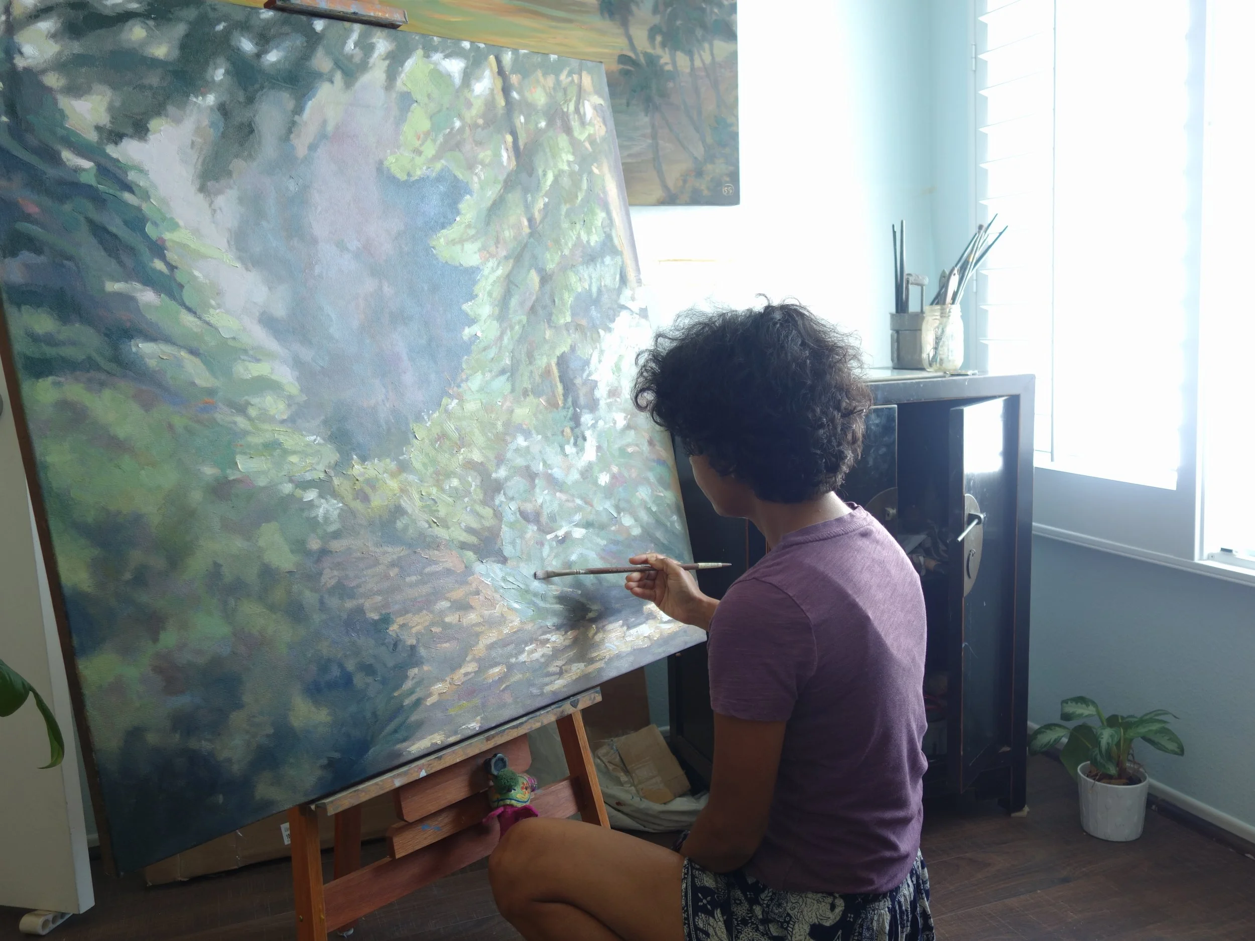Painter working on a mountain landscape painting on an easel