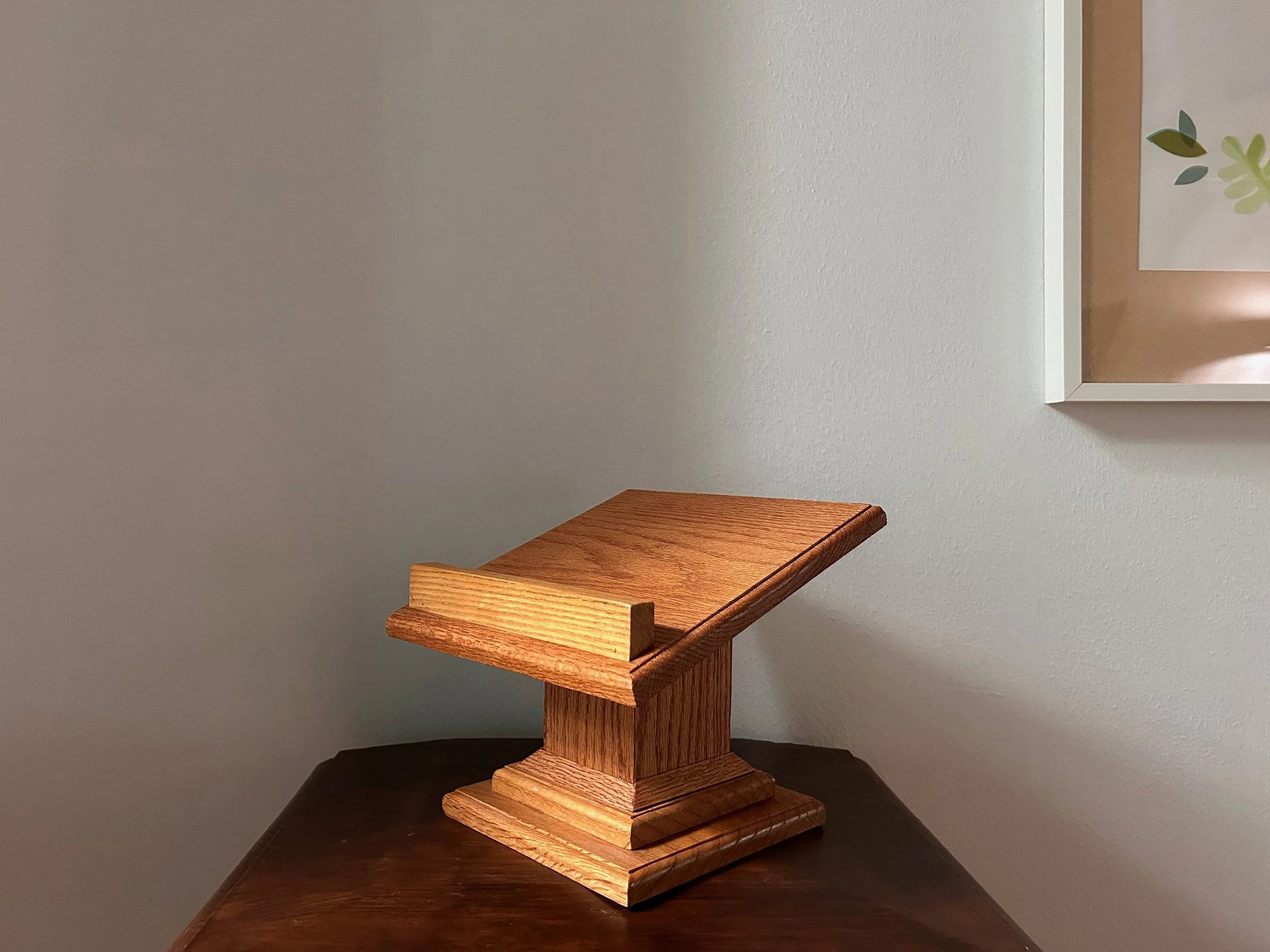 handcrafted wooden book stand with angled top and raised lip, finished in warm natural wood