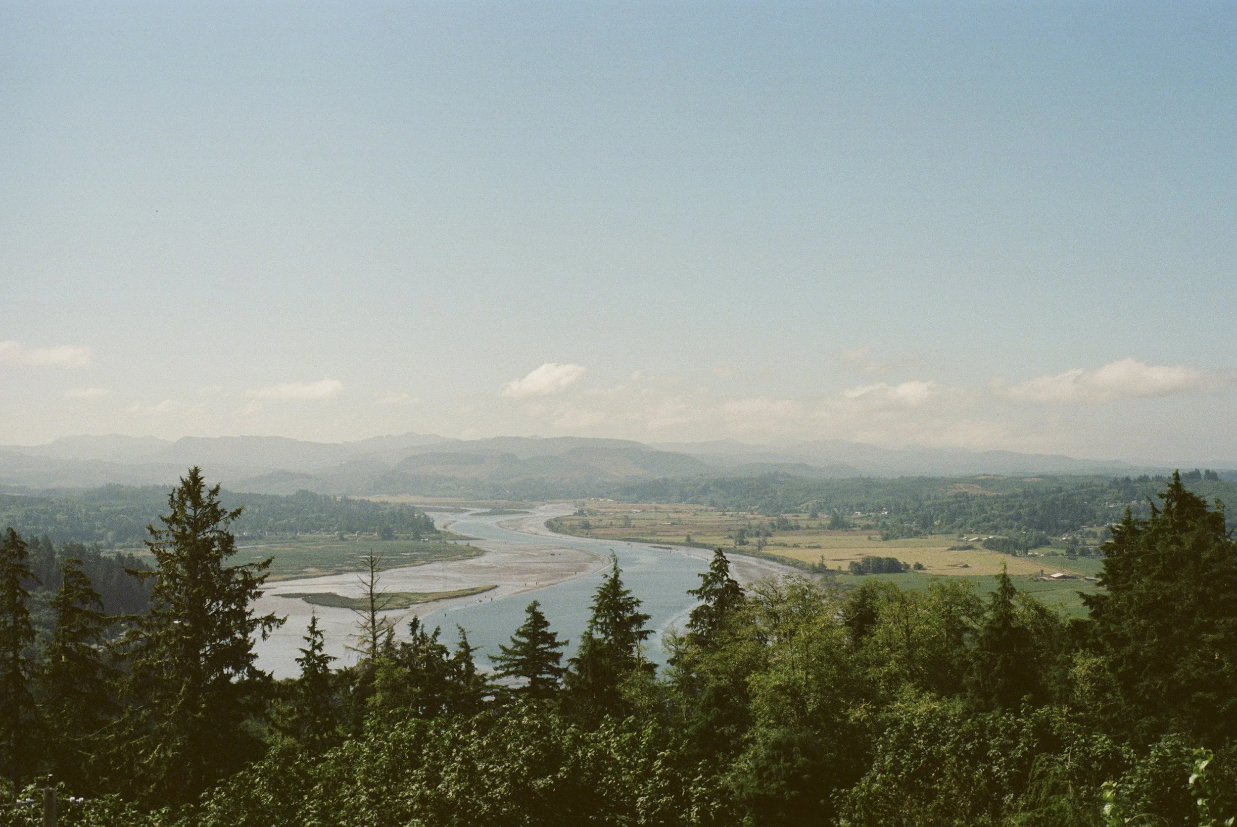 A scene of a film photograph of a  blue river and luh green mountains