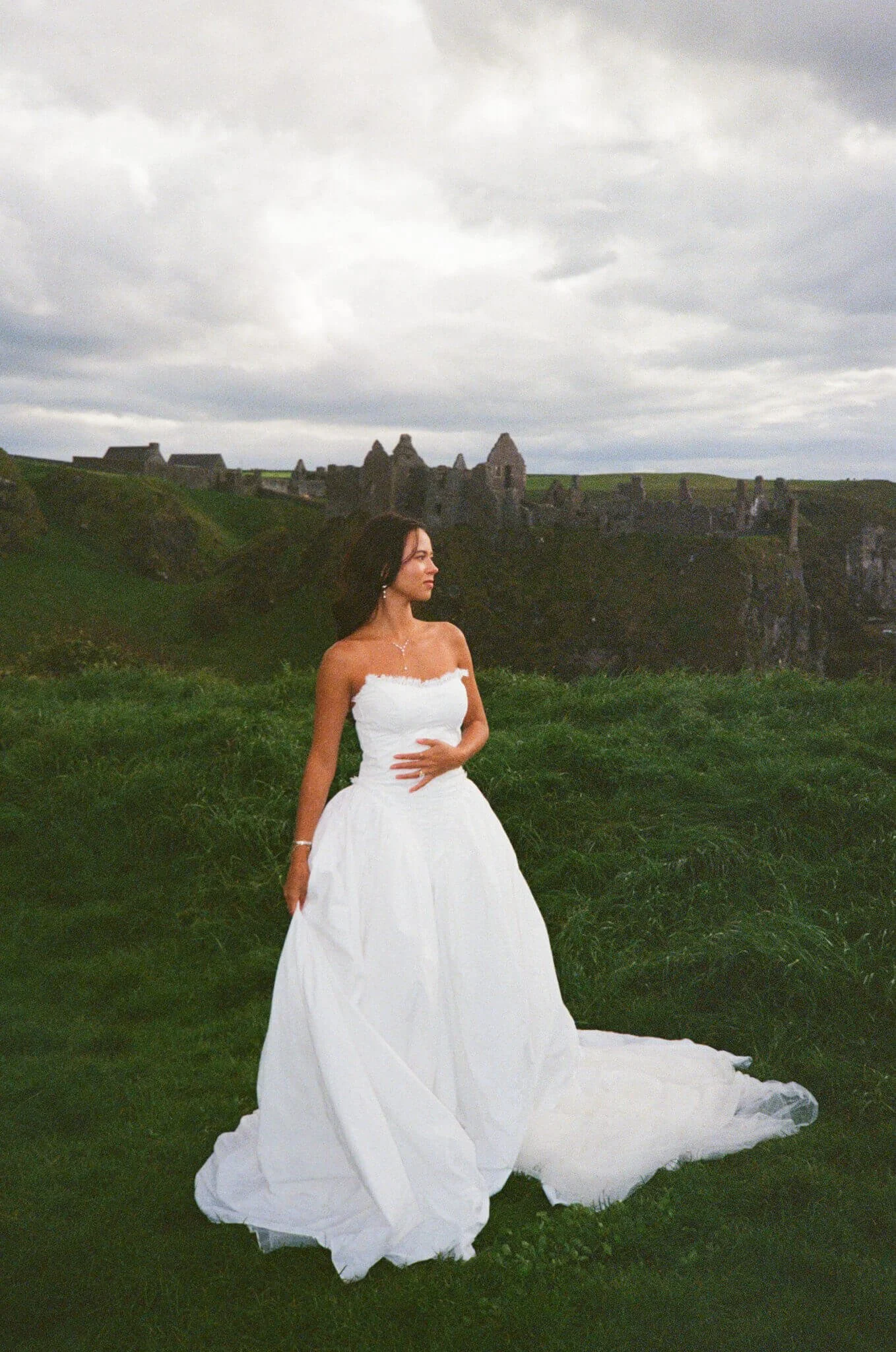 A bride stands in front of a castle in Ireland during her elopement photos