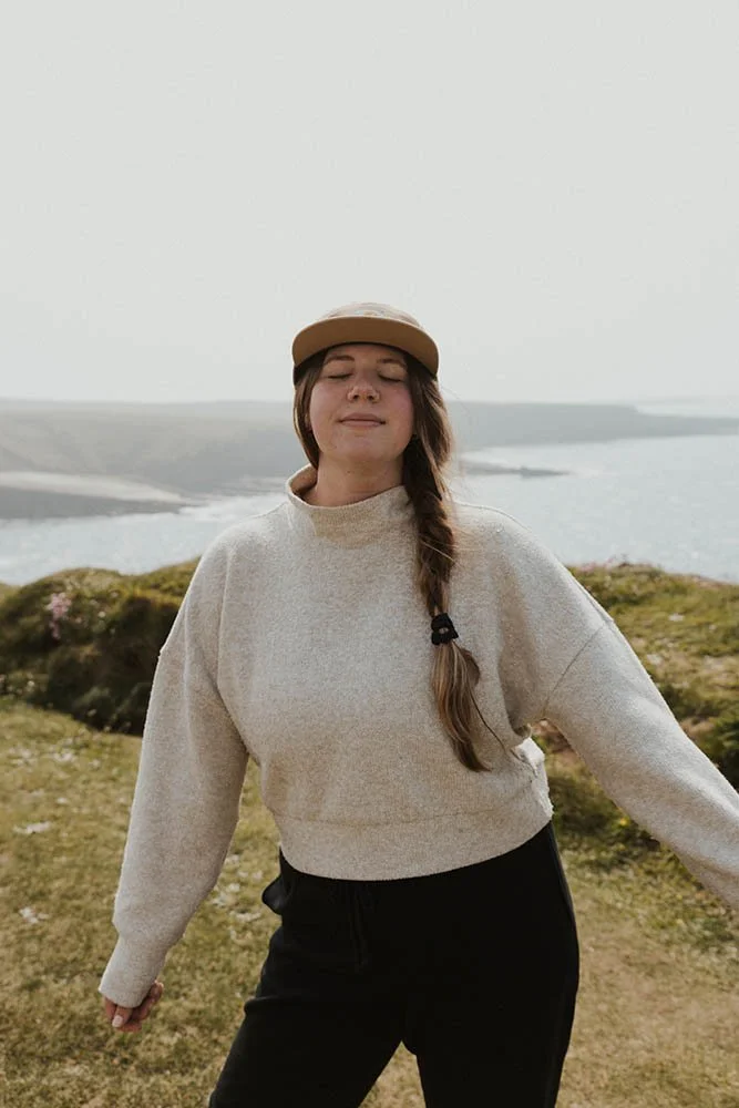 An elopement photographer smiling with her eyes closed on a sunny day on the coast of Ireland