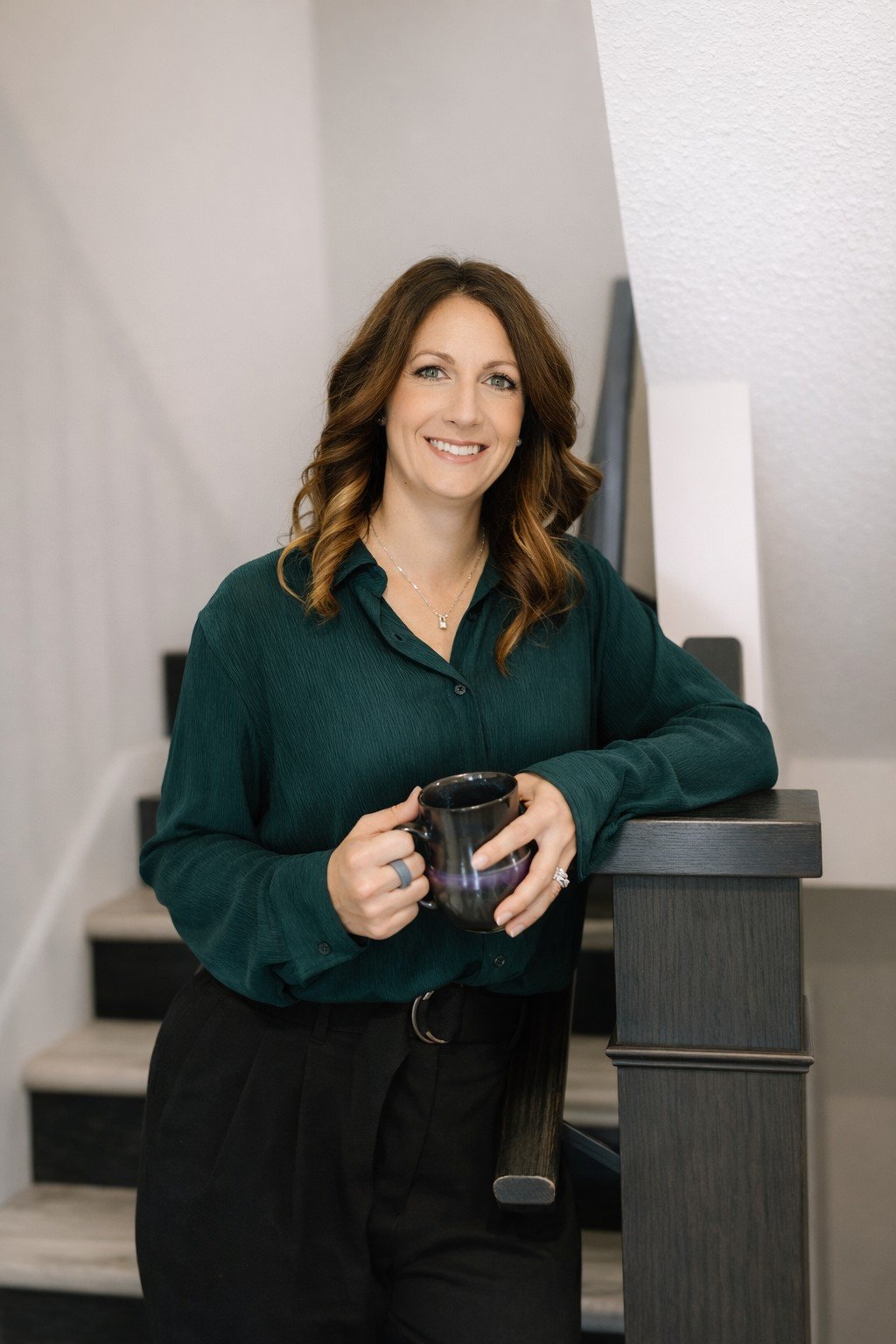 woman leaning on a railing with a warm smile holding a cup of coffee