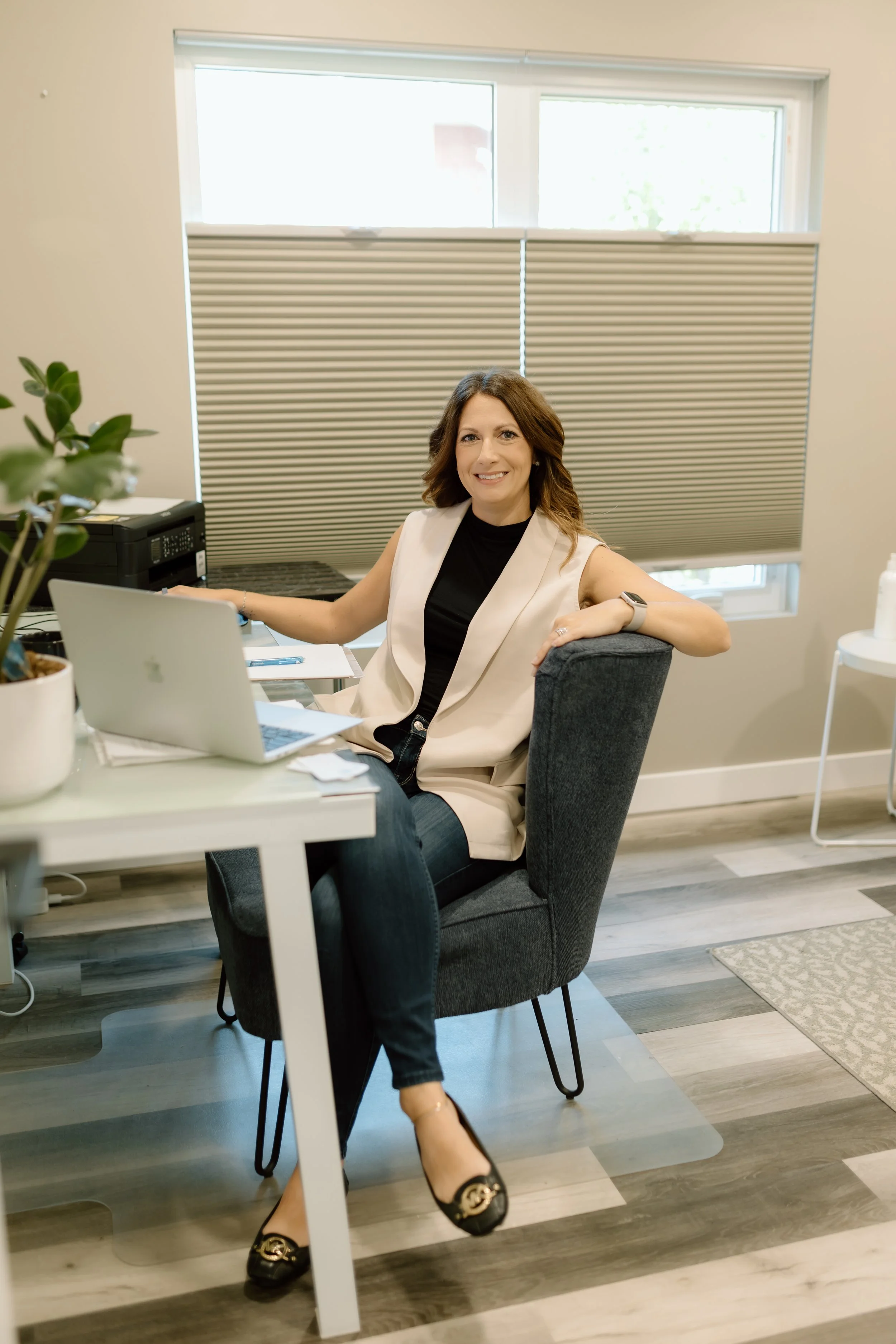 professional therapist woman with a warm smile sitting at a desk with an open laptop
