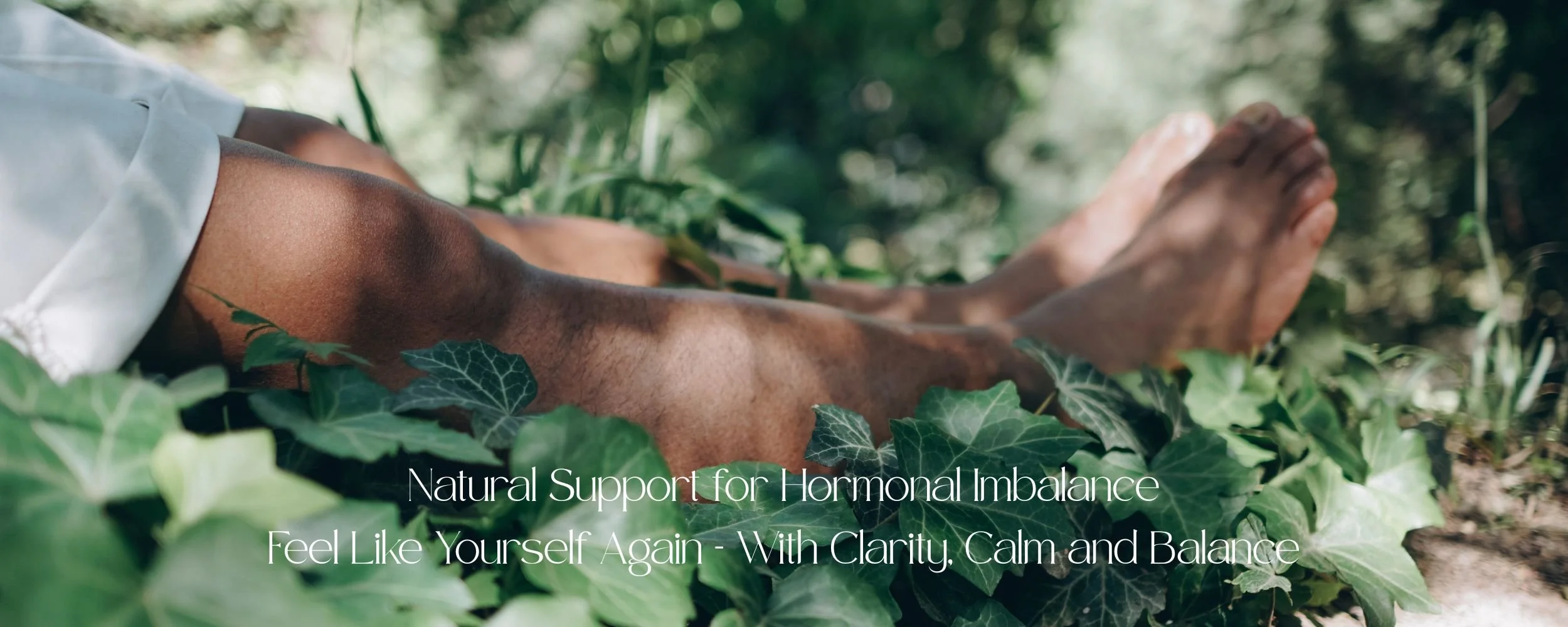 Close-up of a person's legs and feet lying among green leaves outdoors, suggesting relaxation or grounding in nature