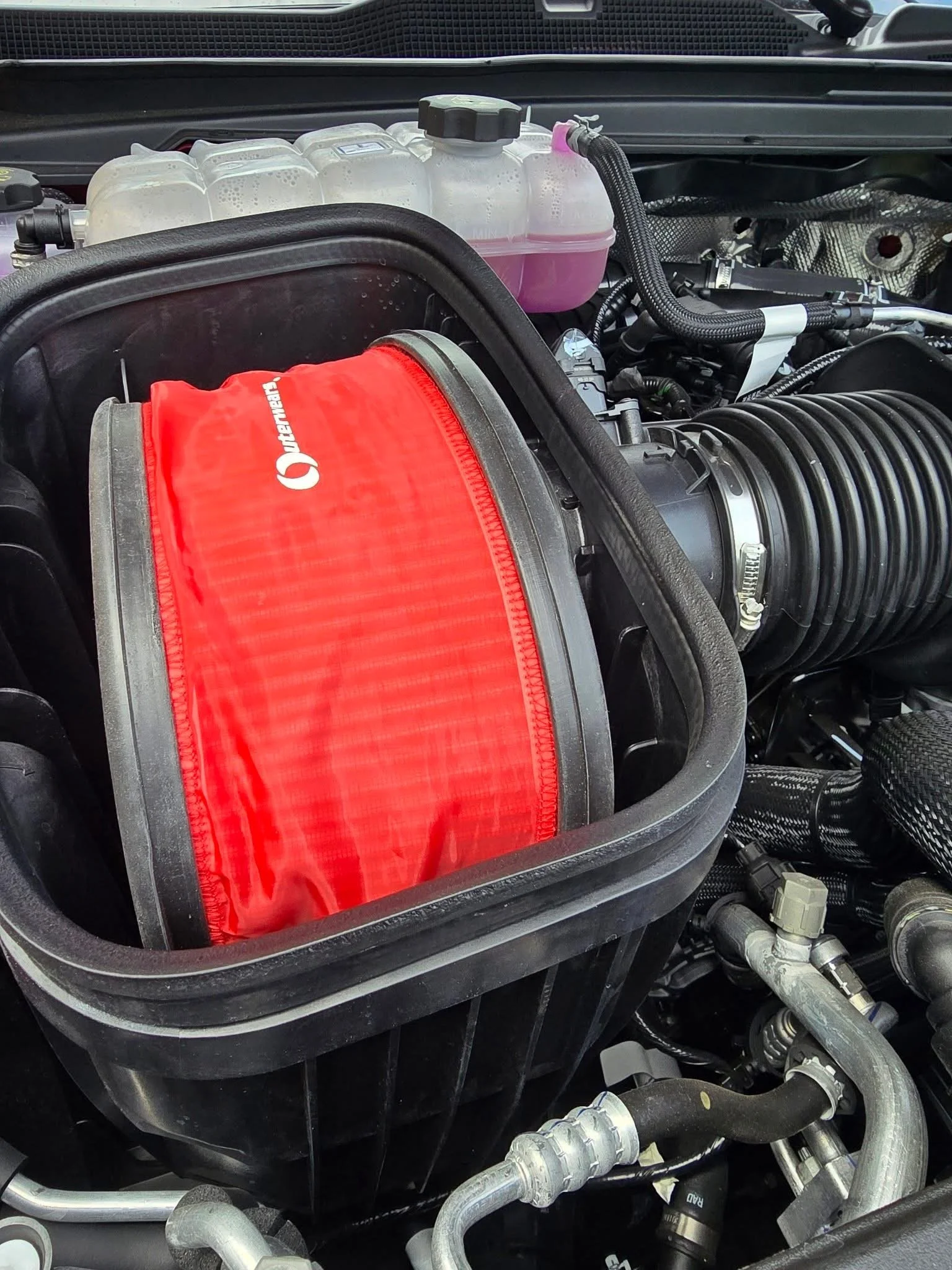 Red Outerwears pre-filter installed on the OEM engine air filter in a 2025 Ram RHO engine bay.
